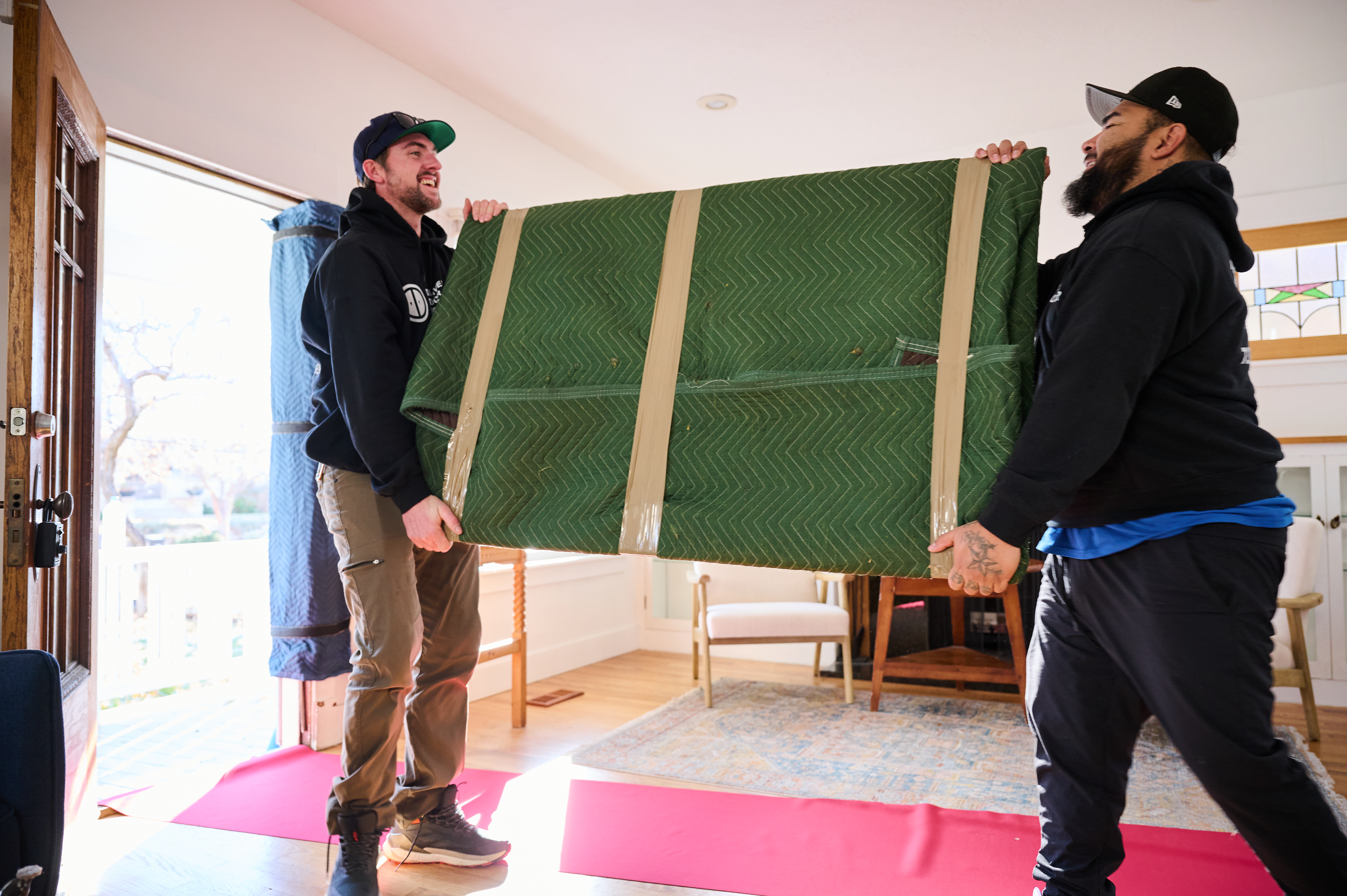 Men moving large wrapped up mirror.