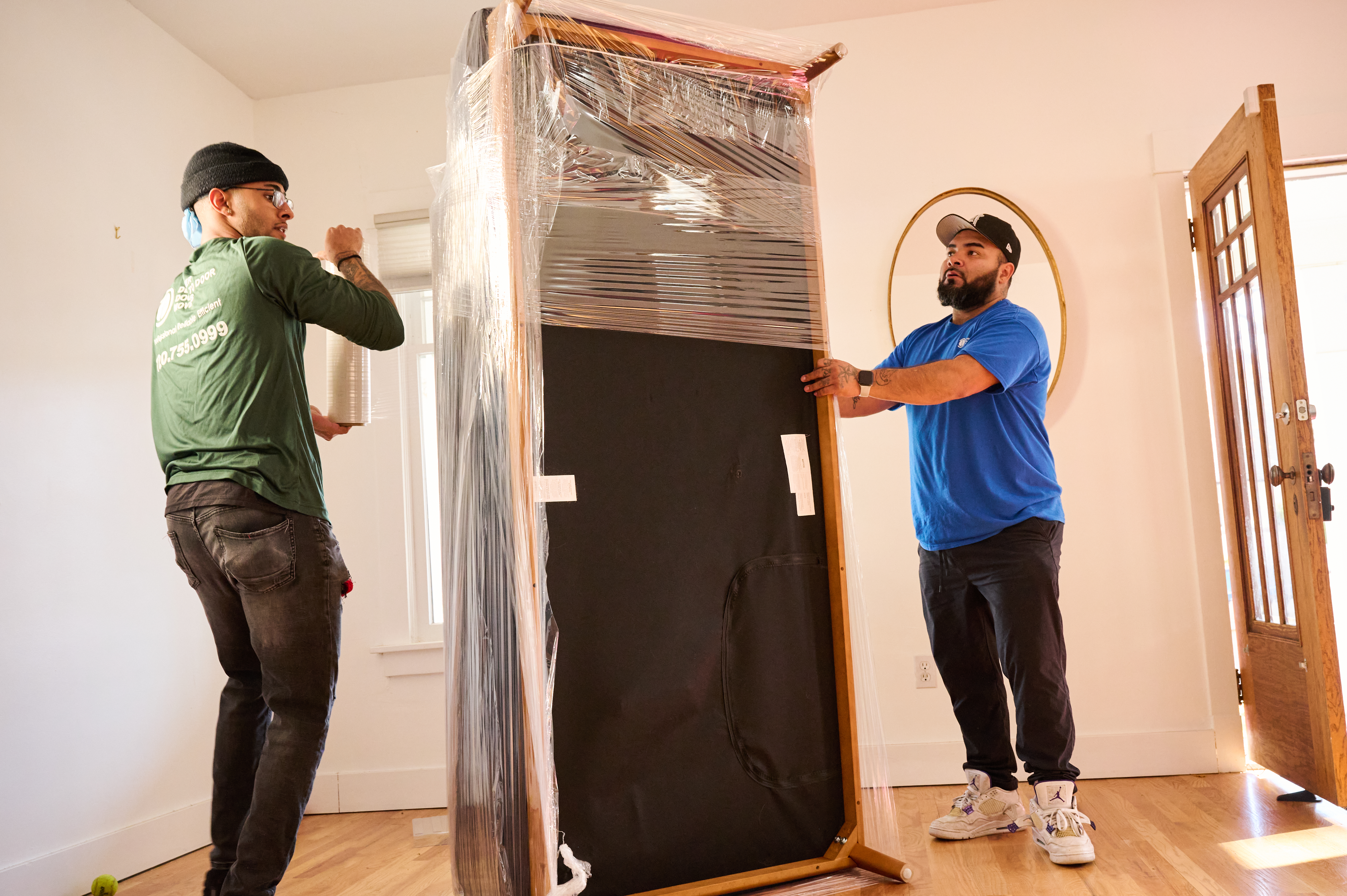 Two movers wrapping up furniture.