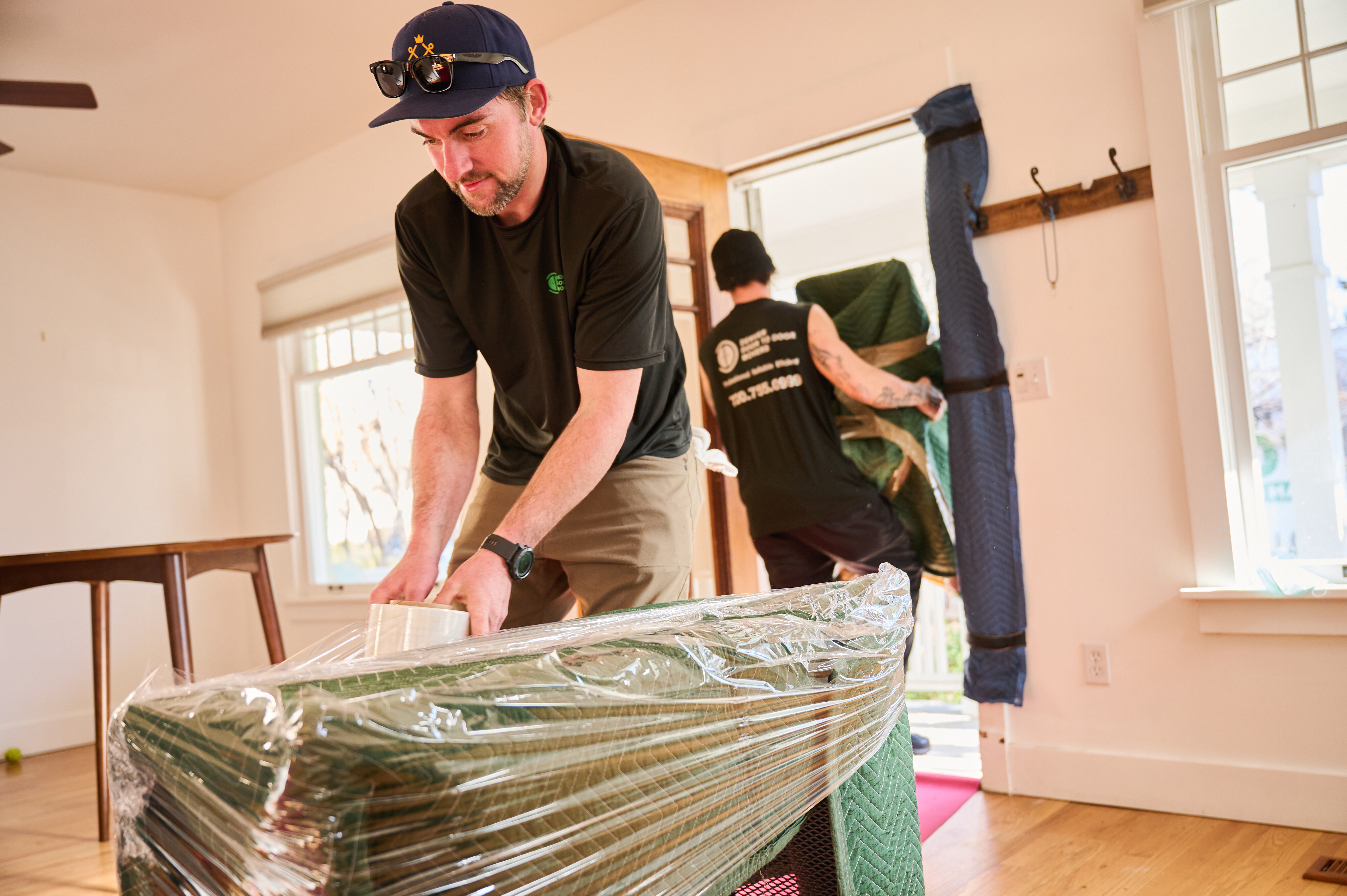 Moving men wrapping furniture for move.