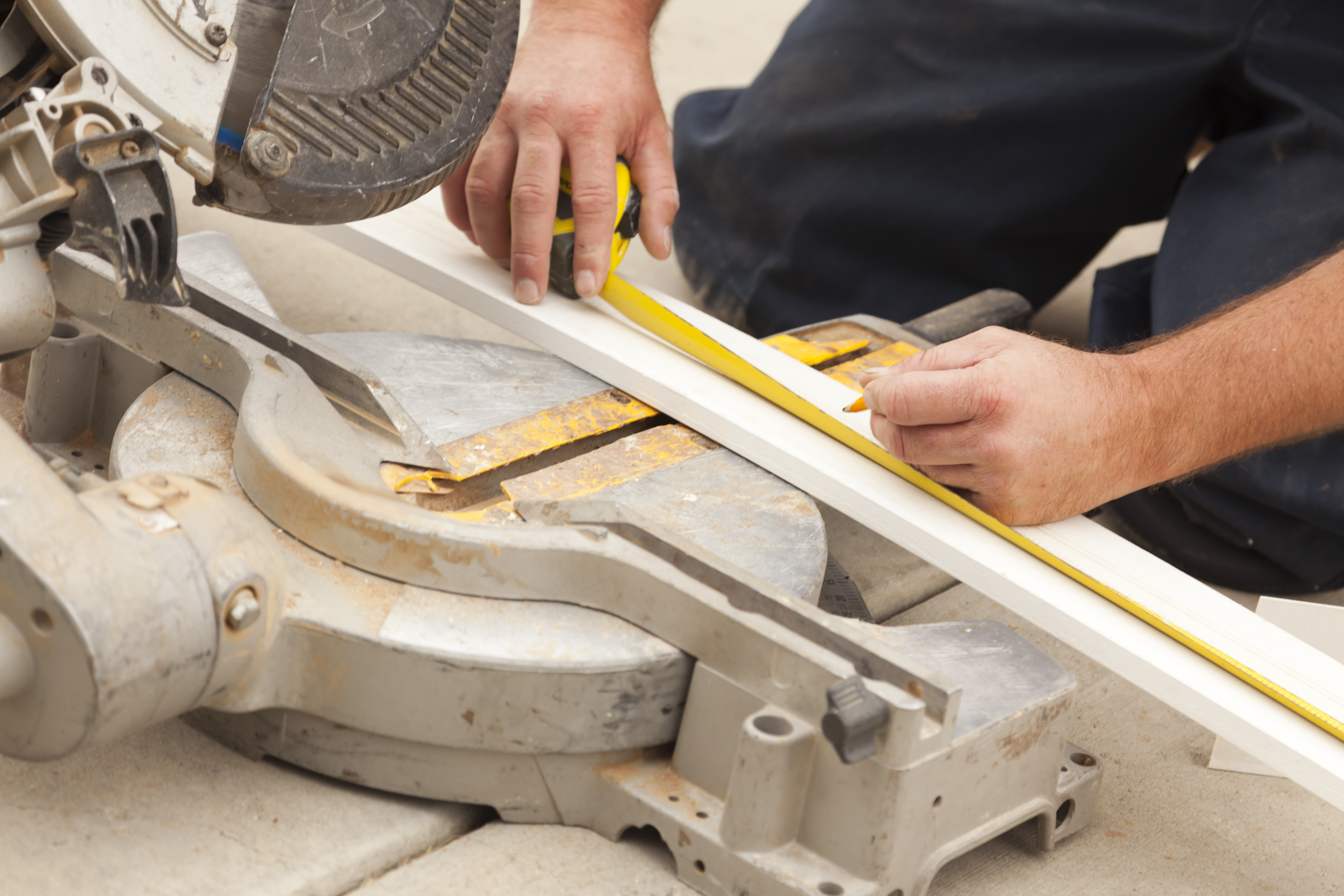 Carpenter measuring baseboard before cutting