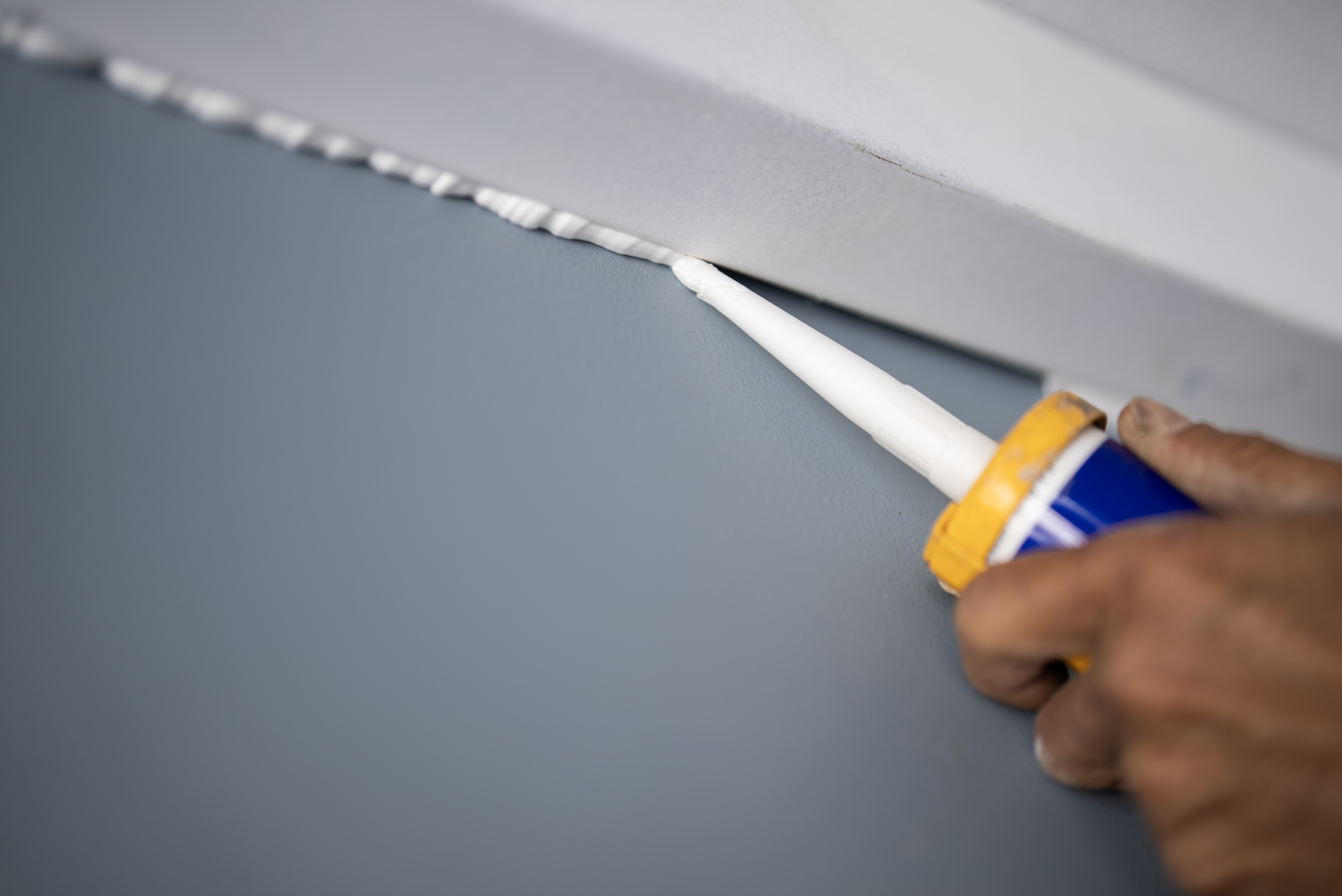 A person caulking a wall corner