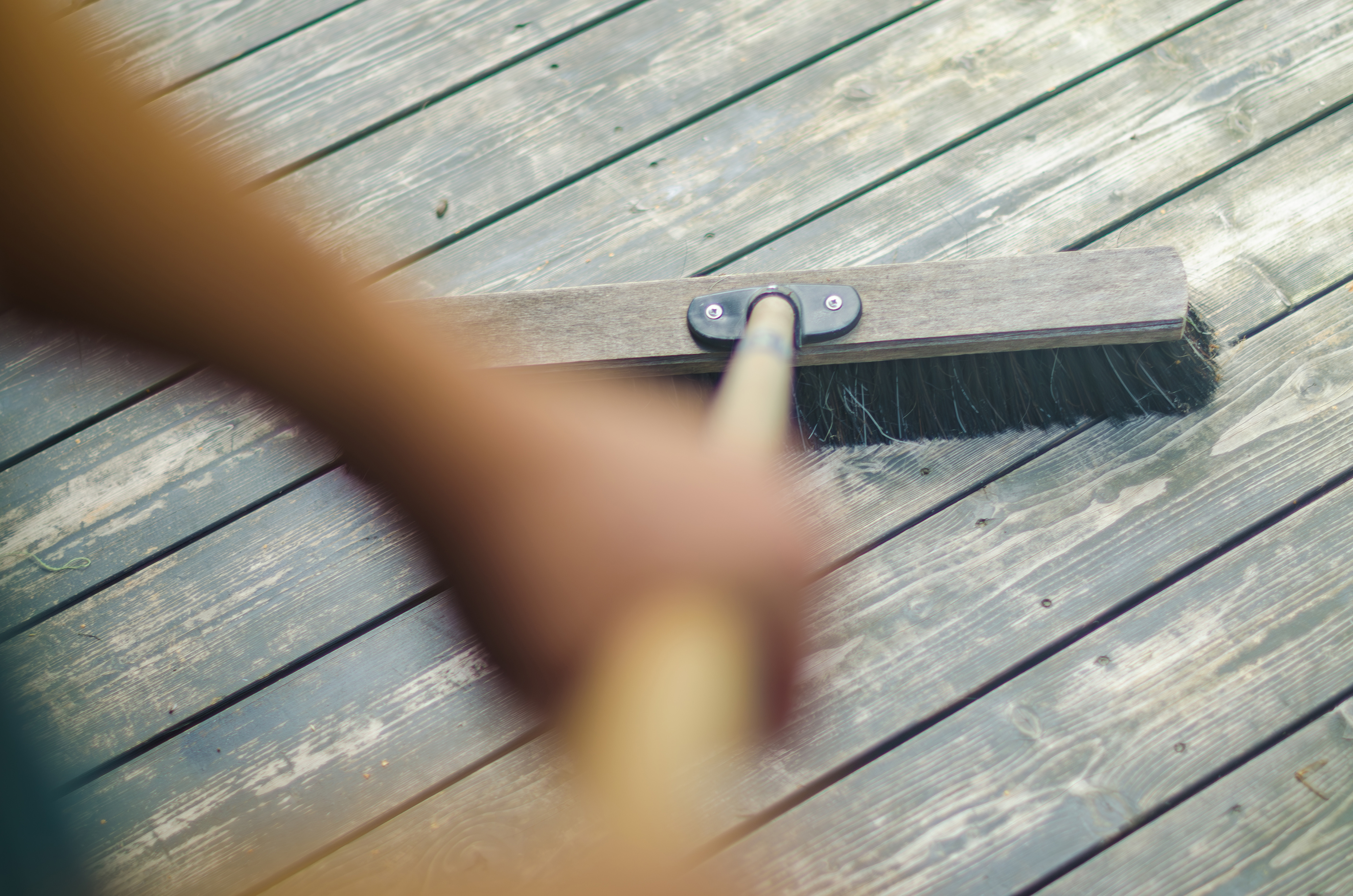 A person sweeping a wooden deck