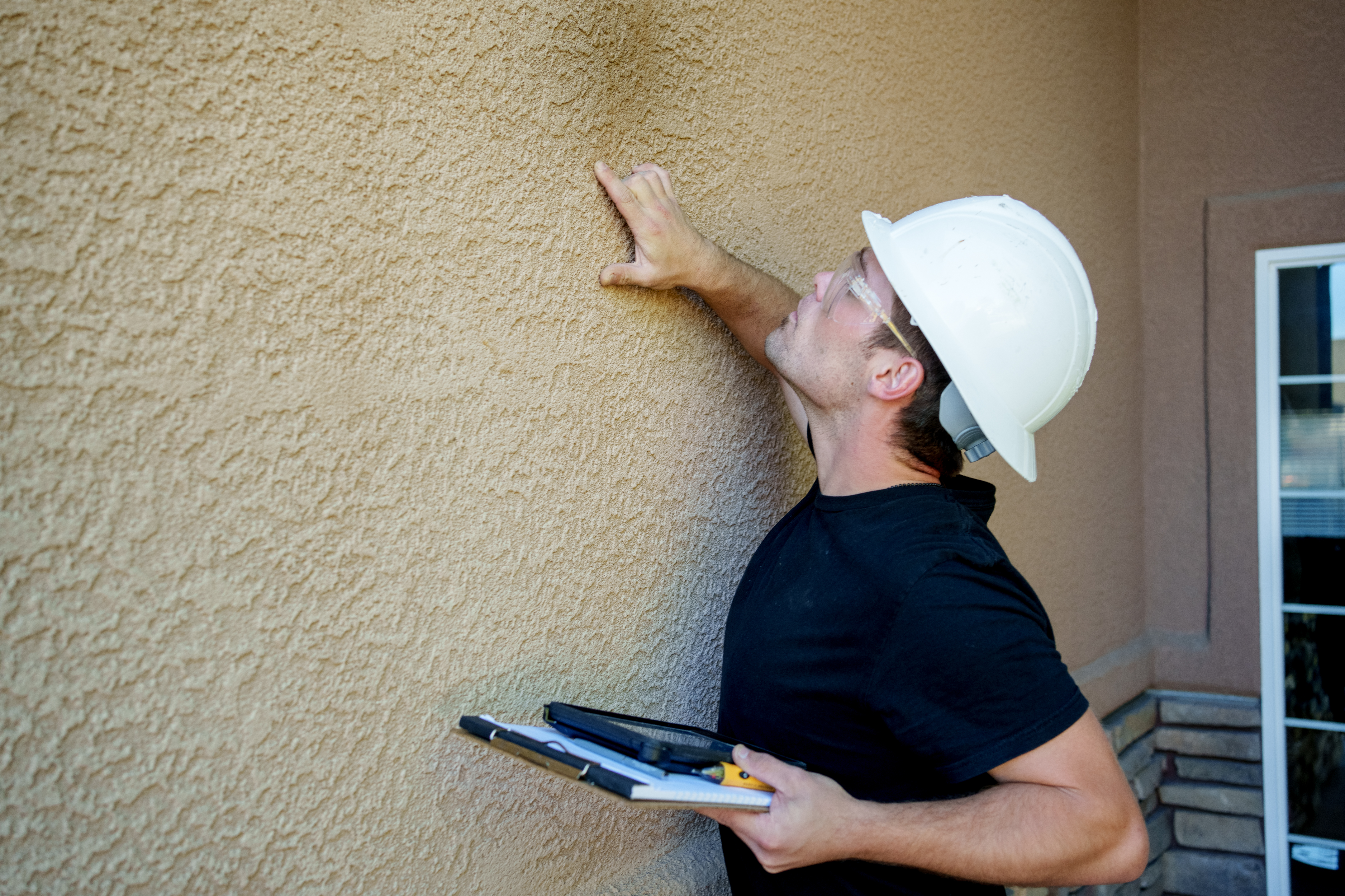A professional inspecting a stucco wall 