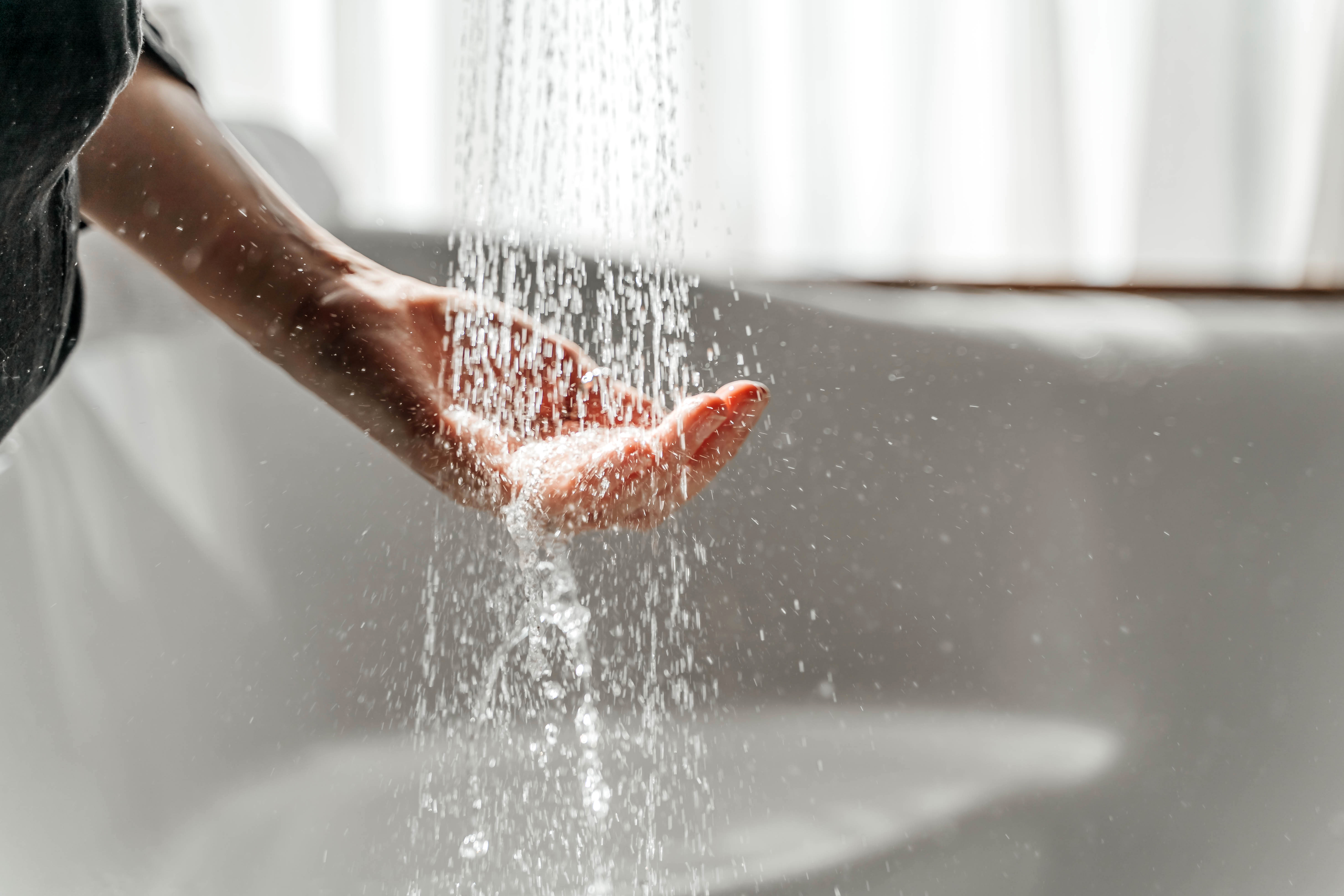 A woman's hand touches the water running from the shower