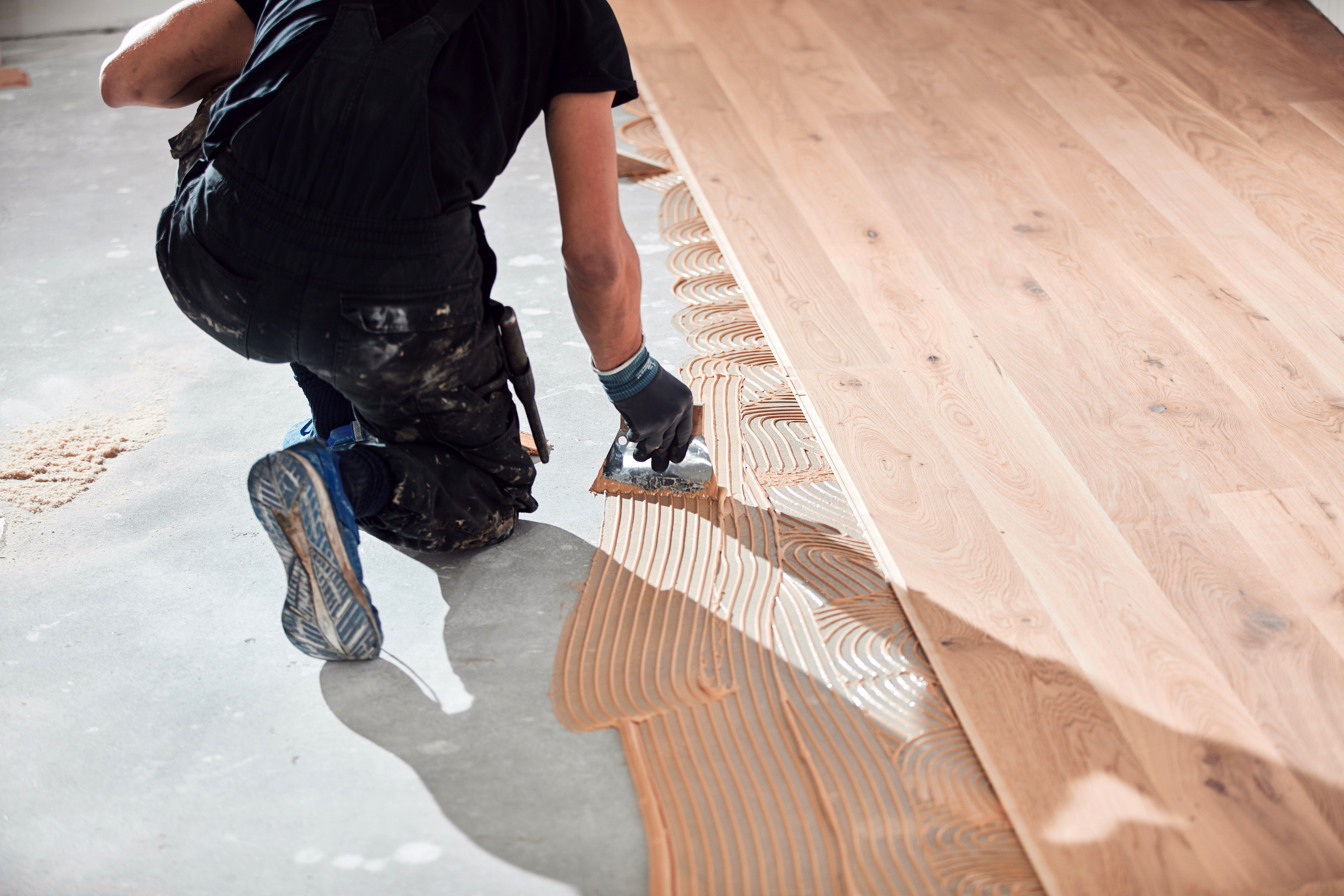 A professional installing hardwood floors over concrete