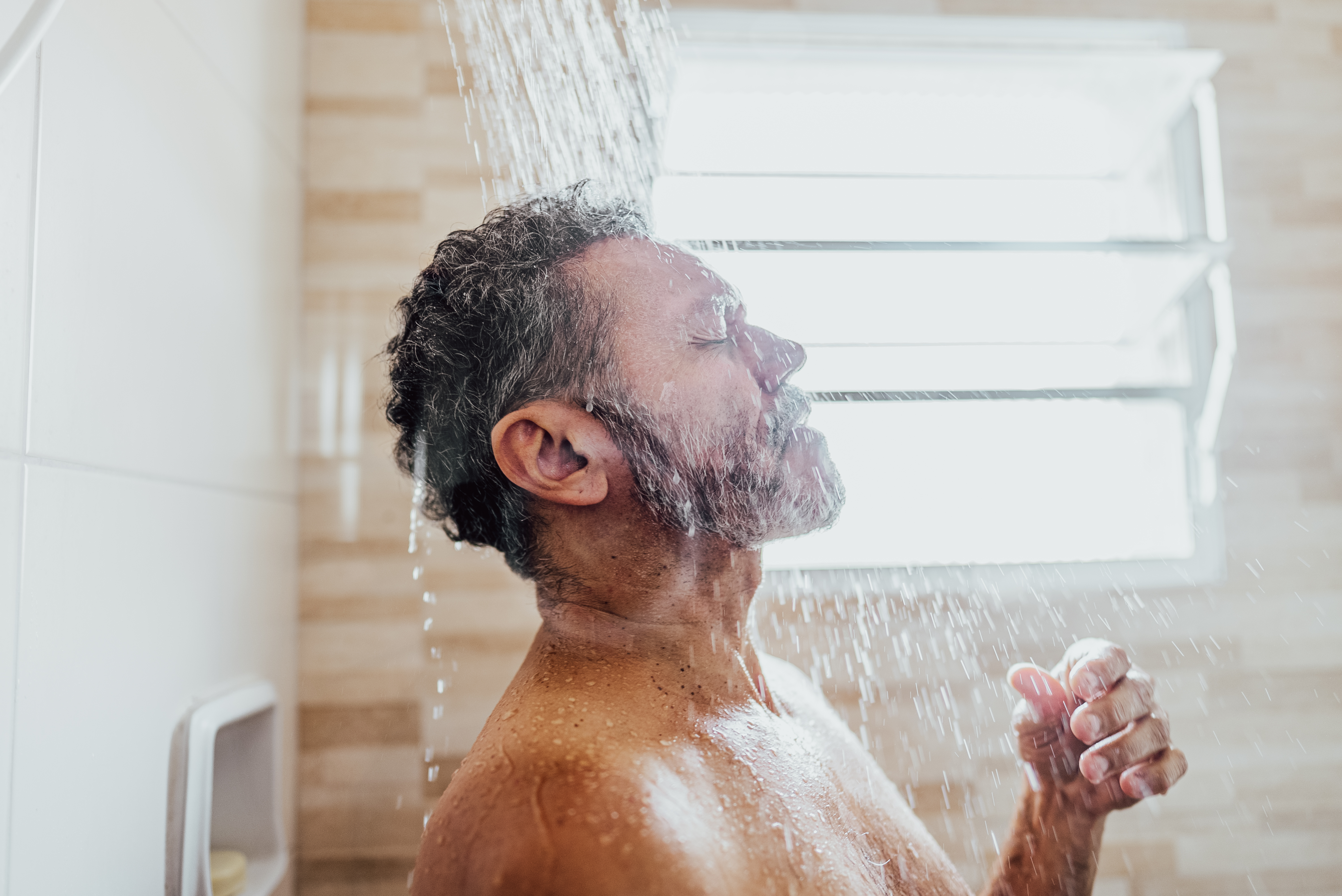 Mature man taking a shower in the bathroom  