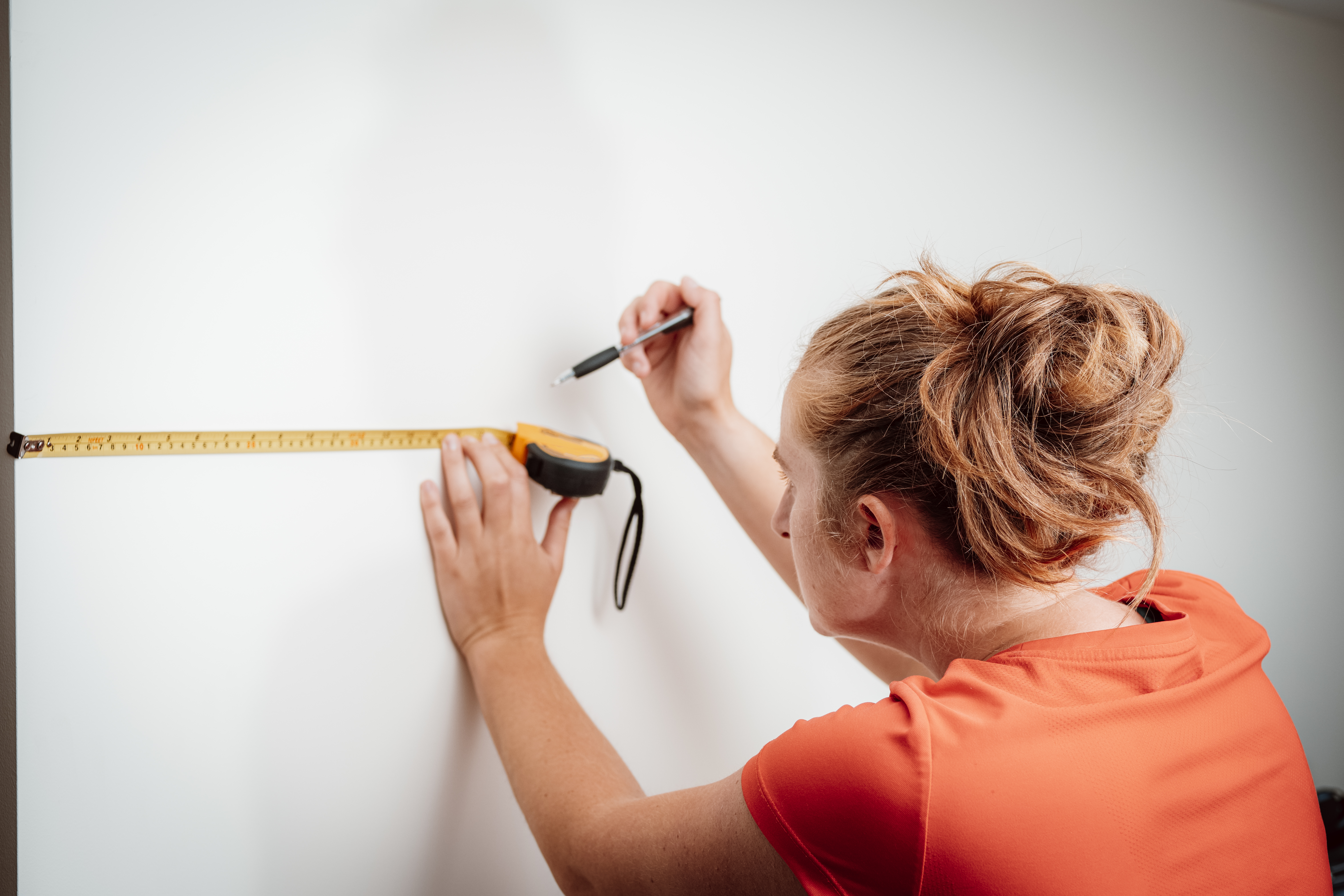 Woman using a tape measure to mark a spot 