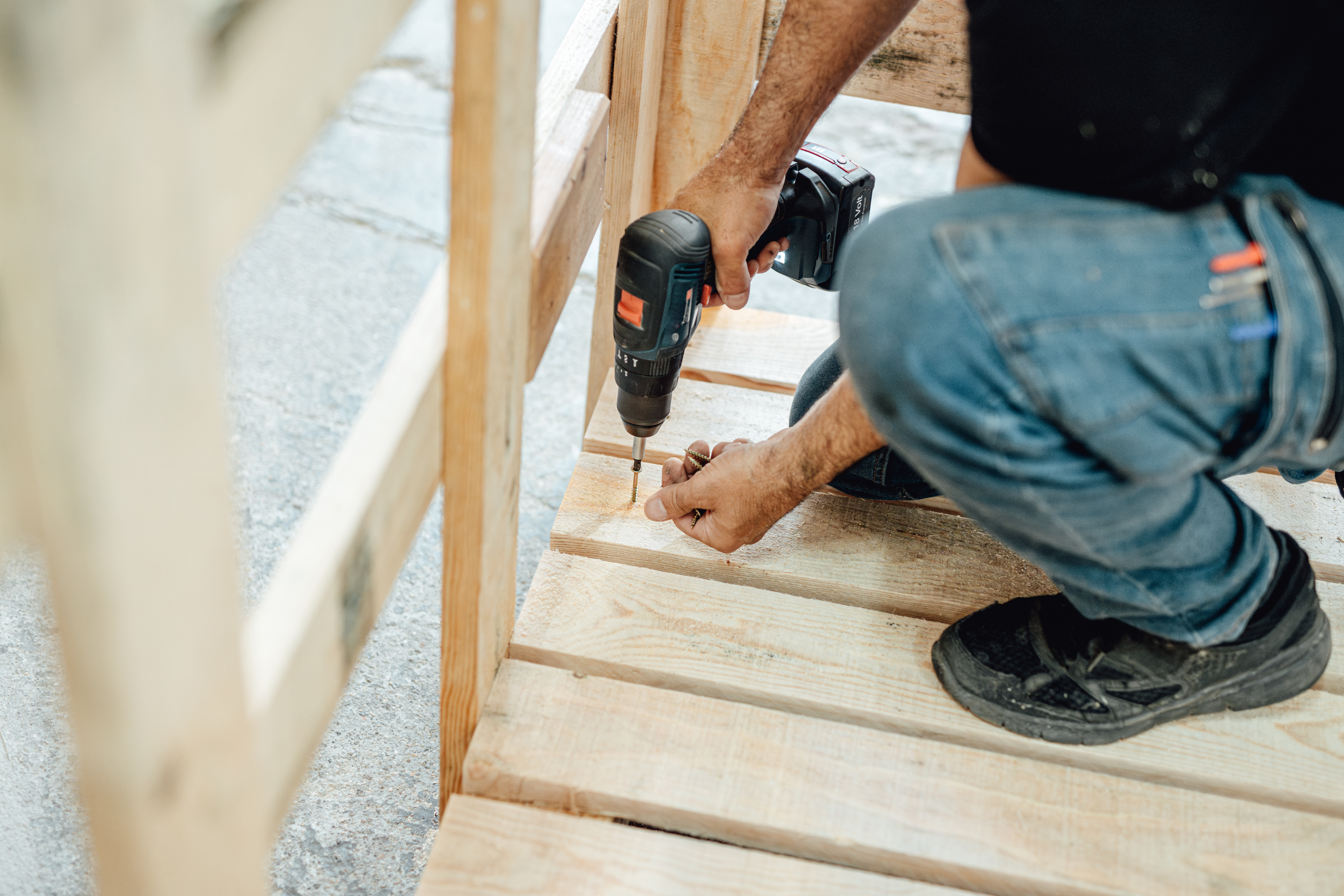 A professional securing wooden boards on deck