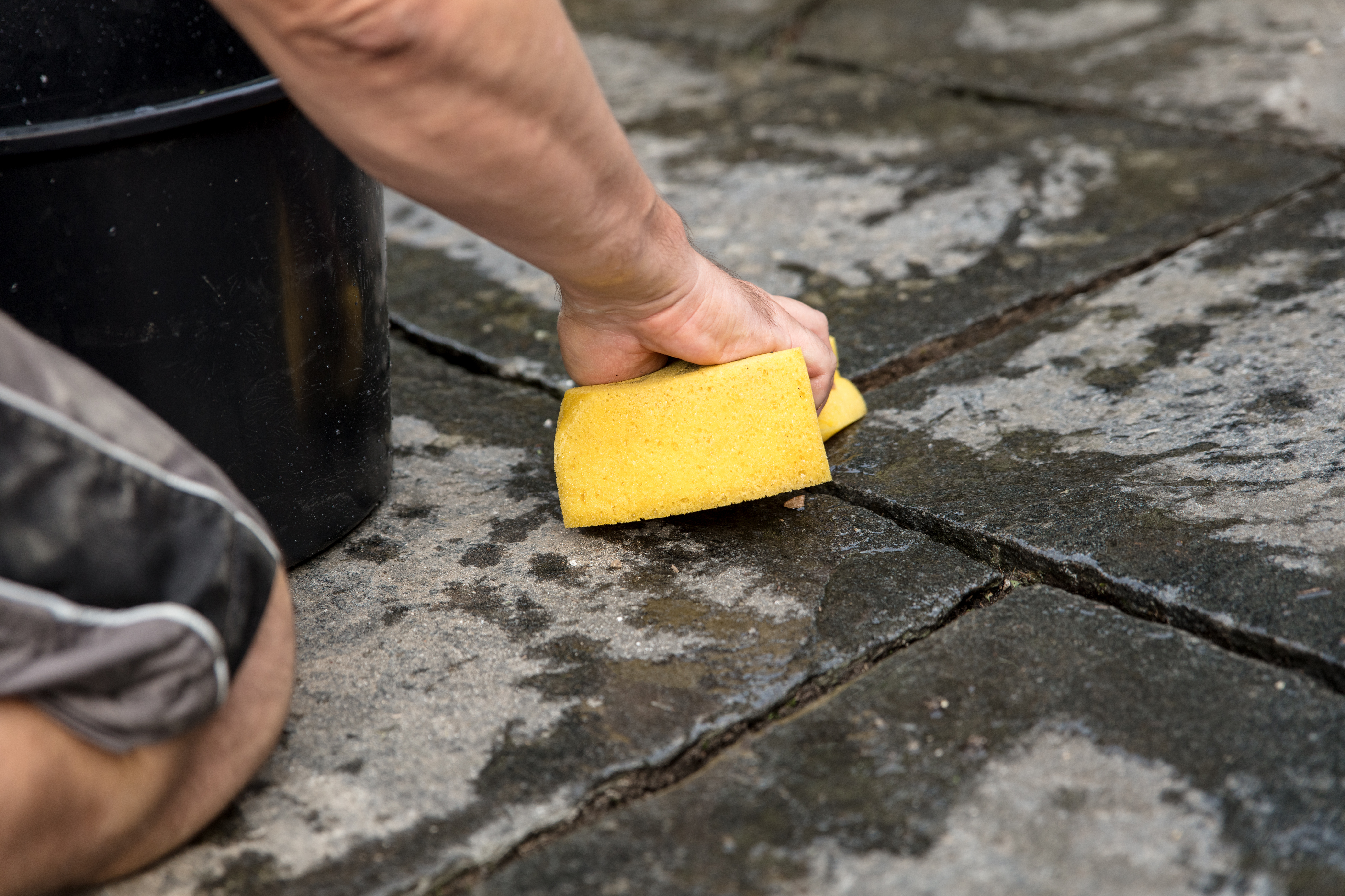 A person cleaning by hand pavers’ joints