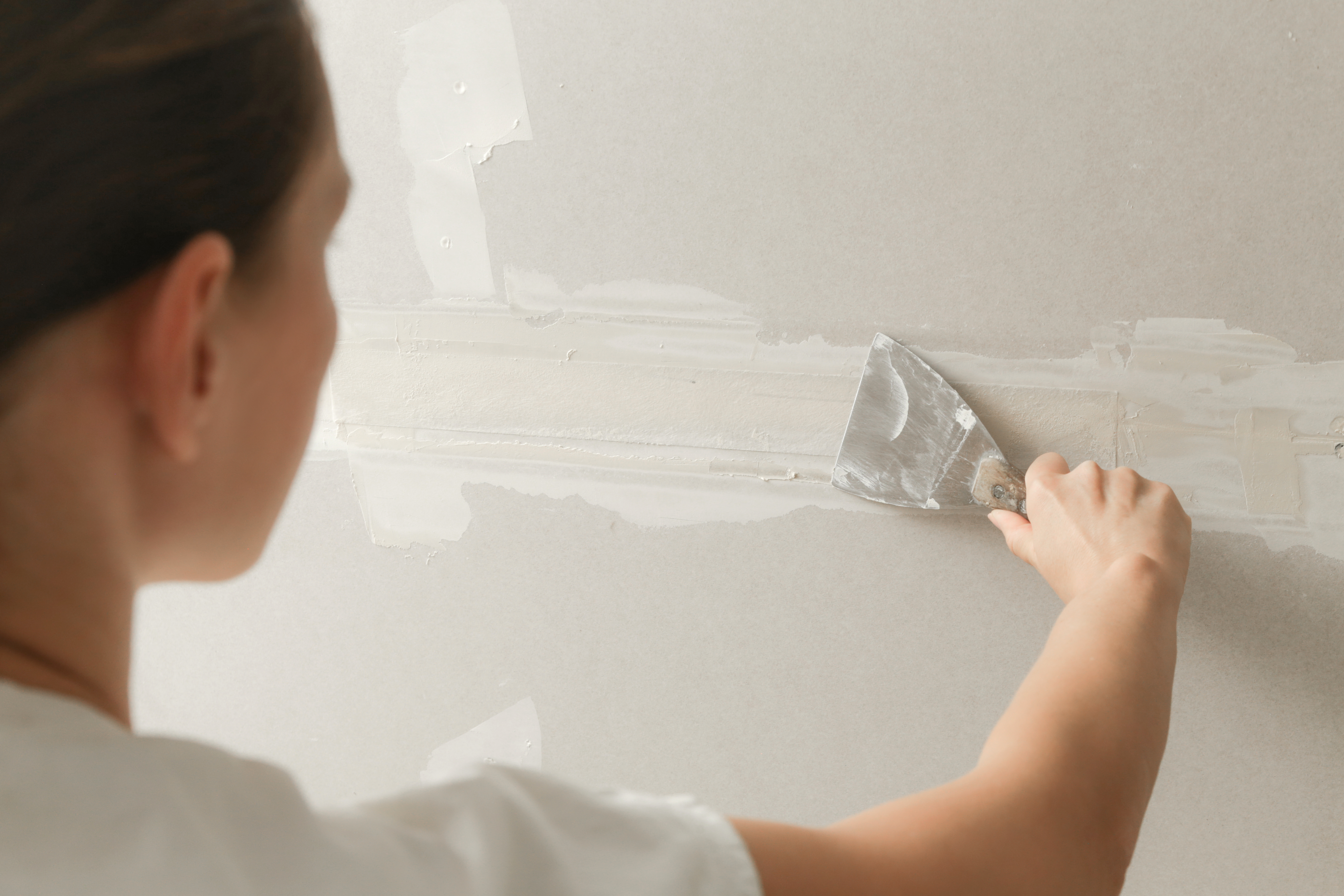 A woman mudding a drywall
