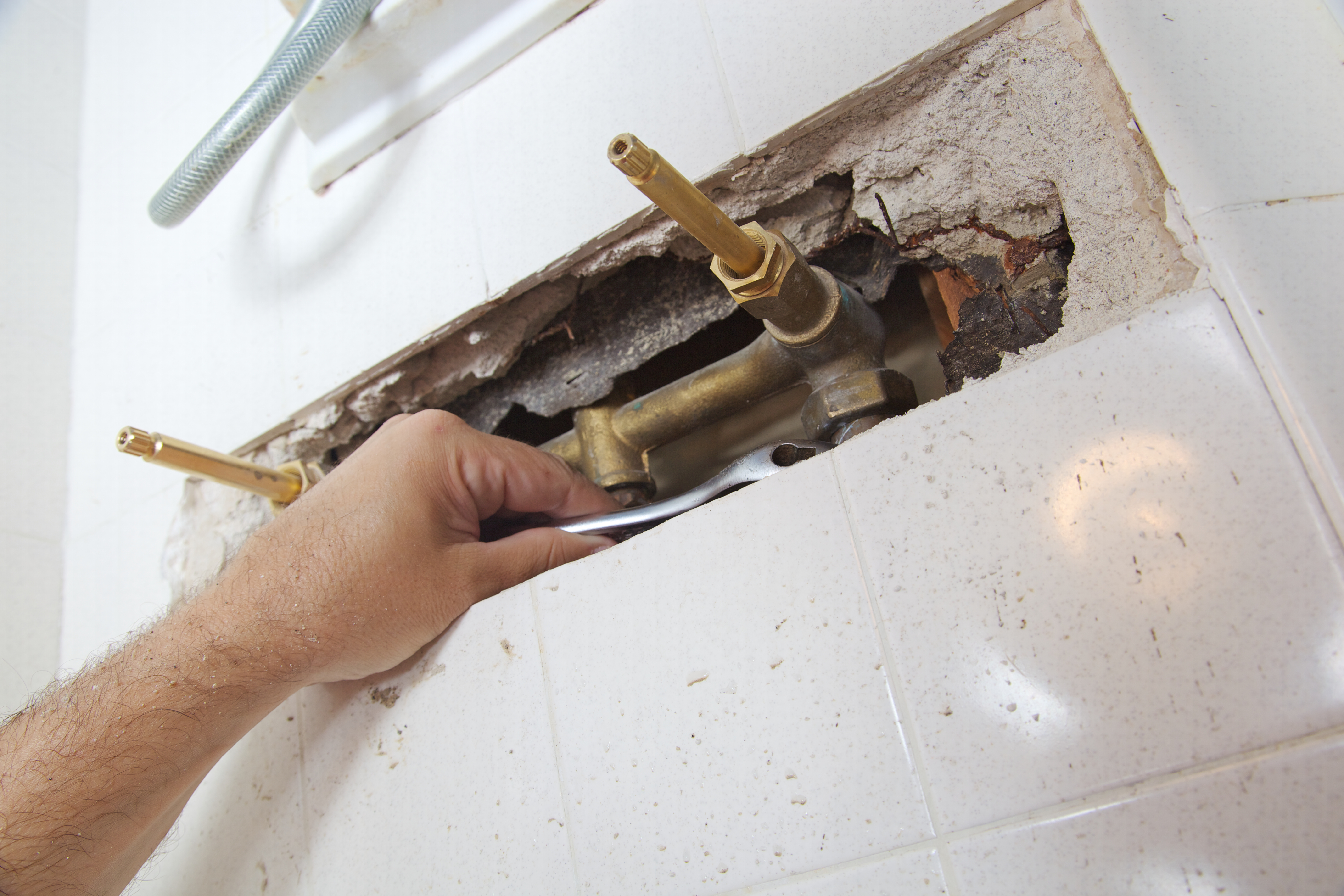 A professional inspecting water pipes of a bathtub