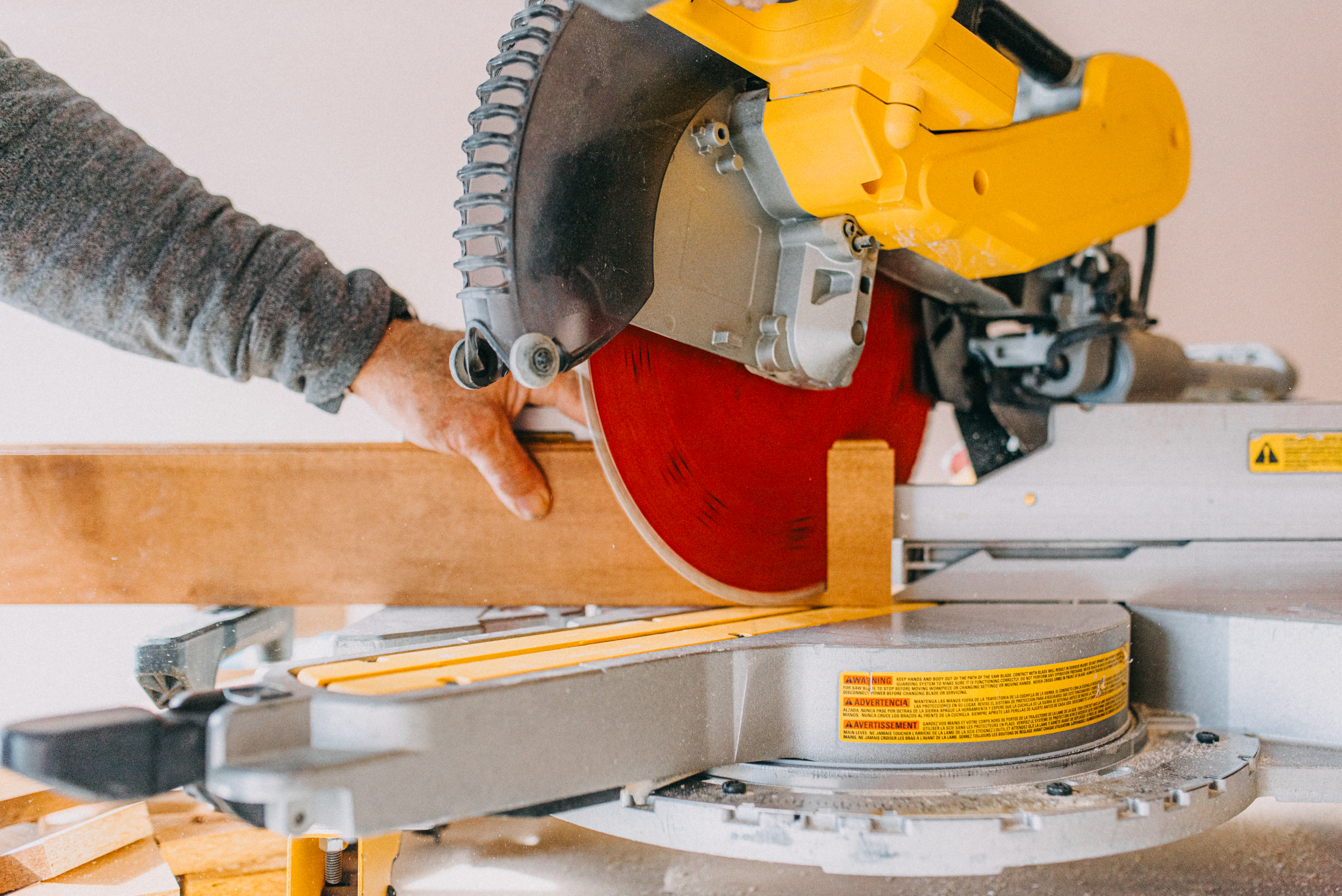 A man cutting a wooden baseboard with a miter saw