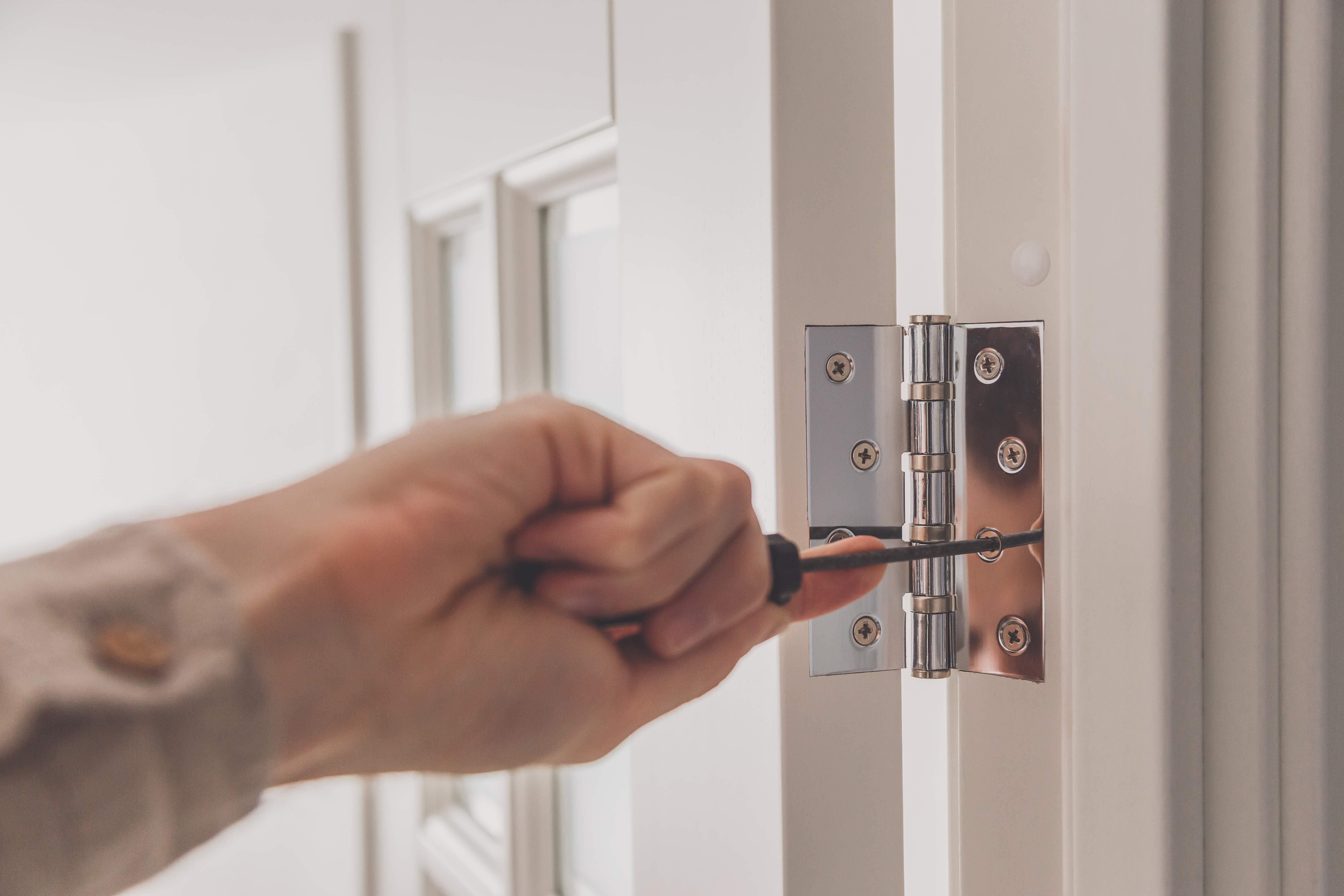 Man removing stainless door hinges 