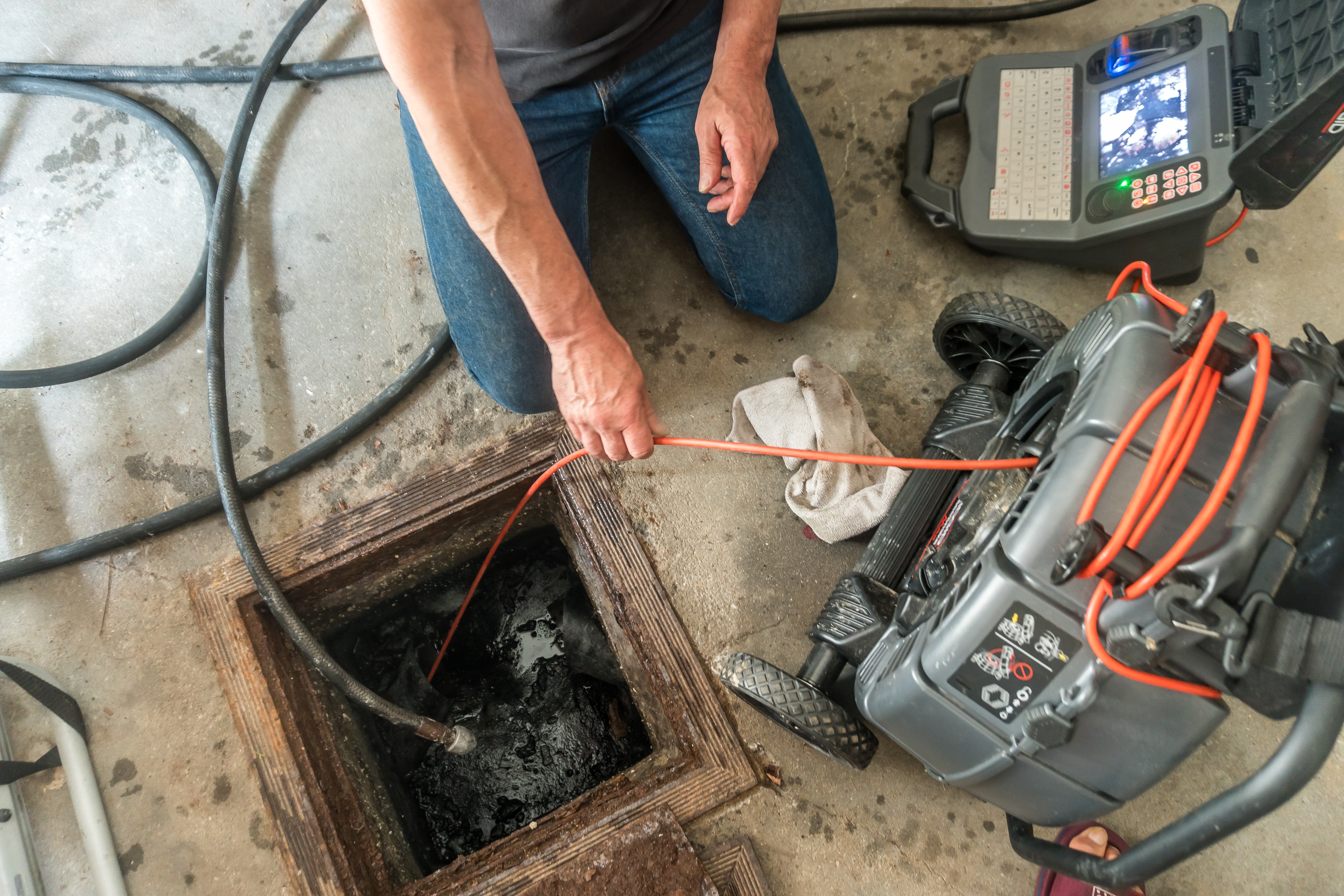 A plumber using professional equipment to repair a sewage system
