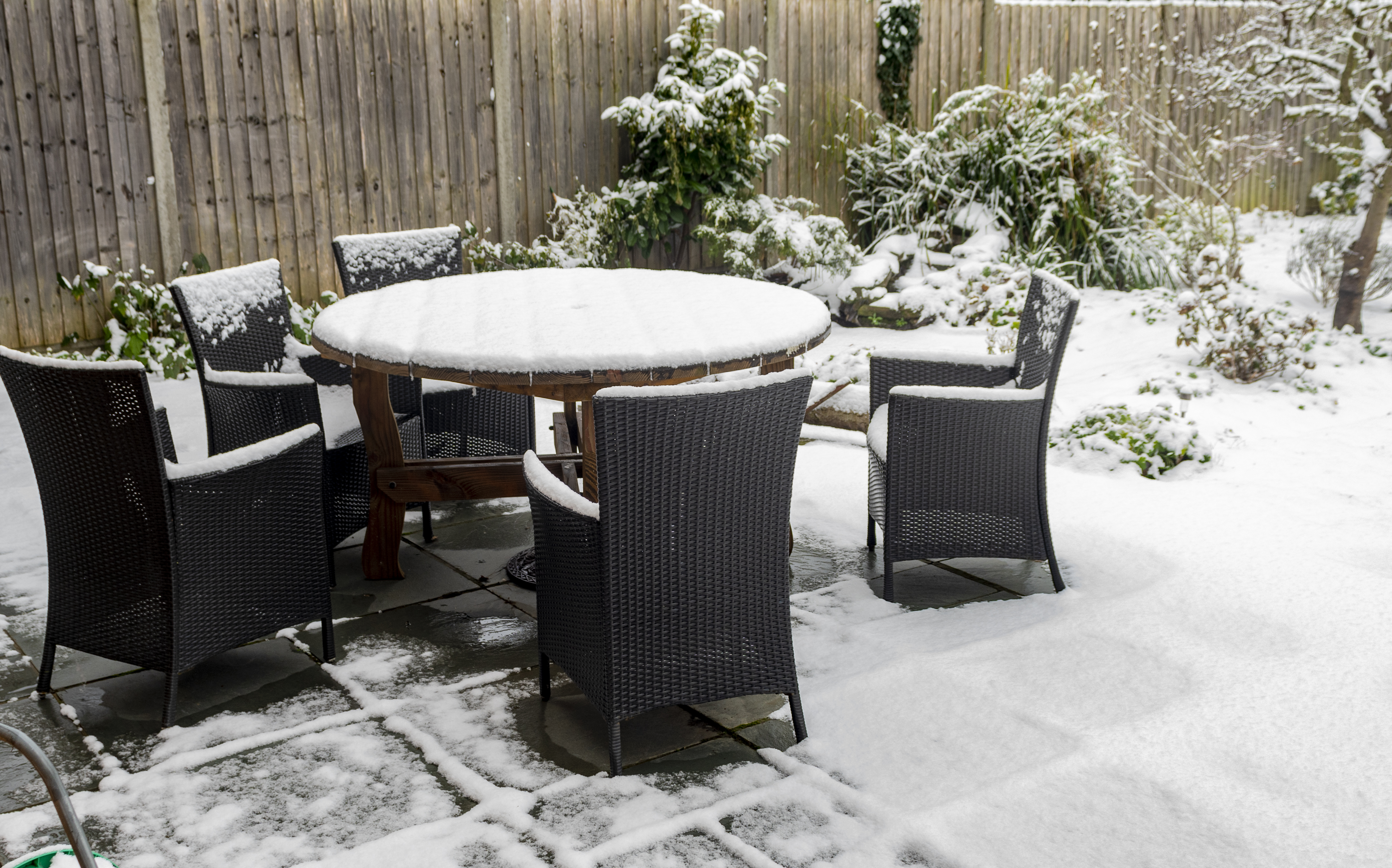 Outdoor furniture sitting on a patio covered with snow