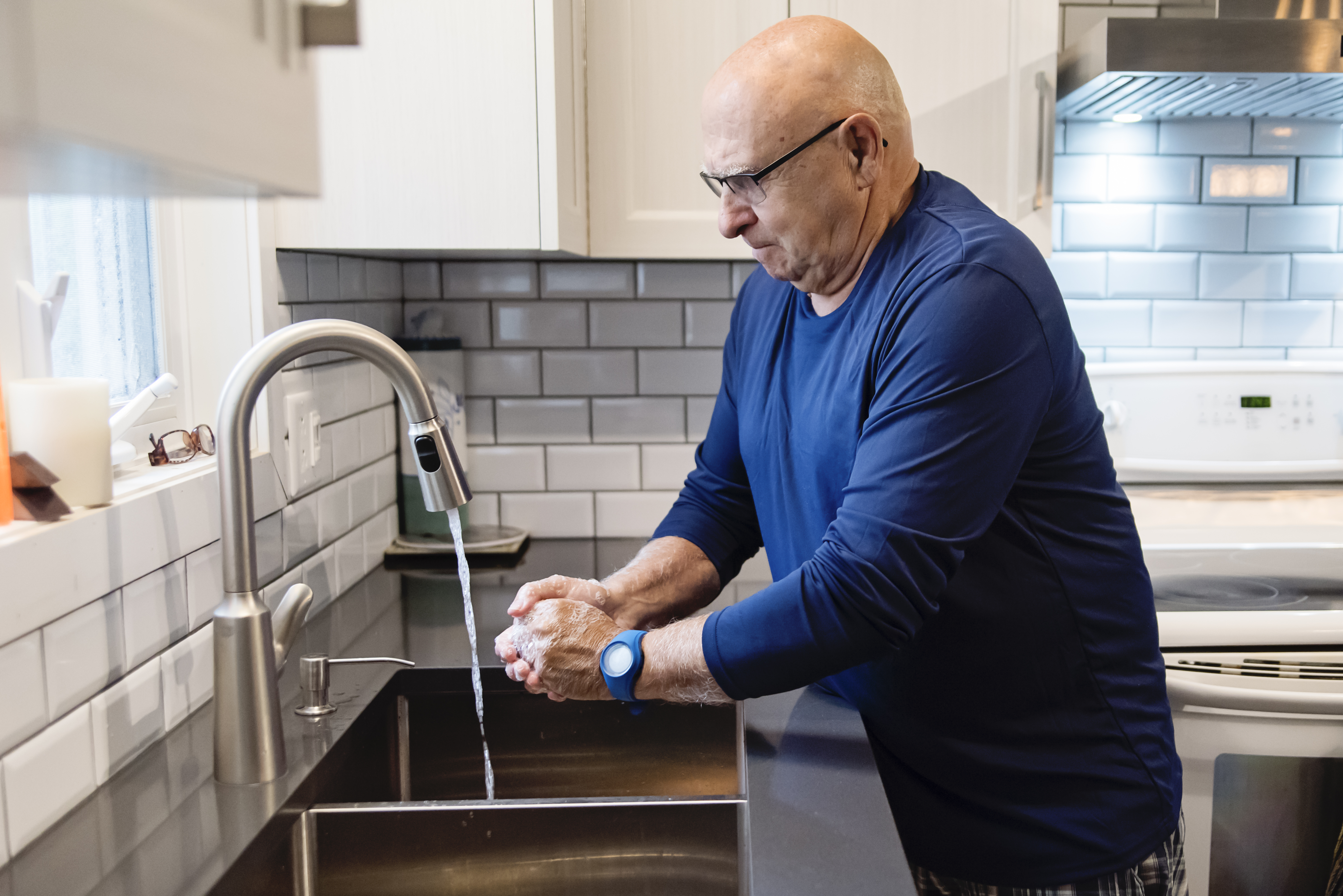 Senior man washing hands in the kitchen sink