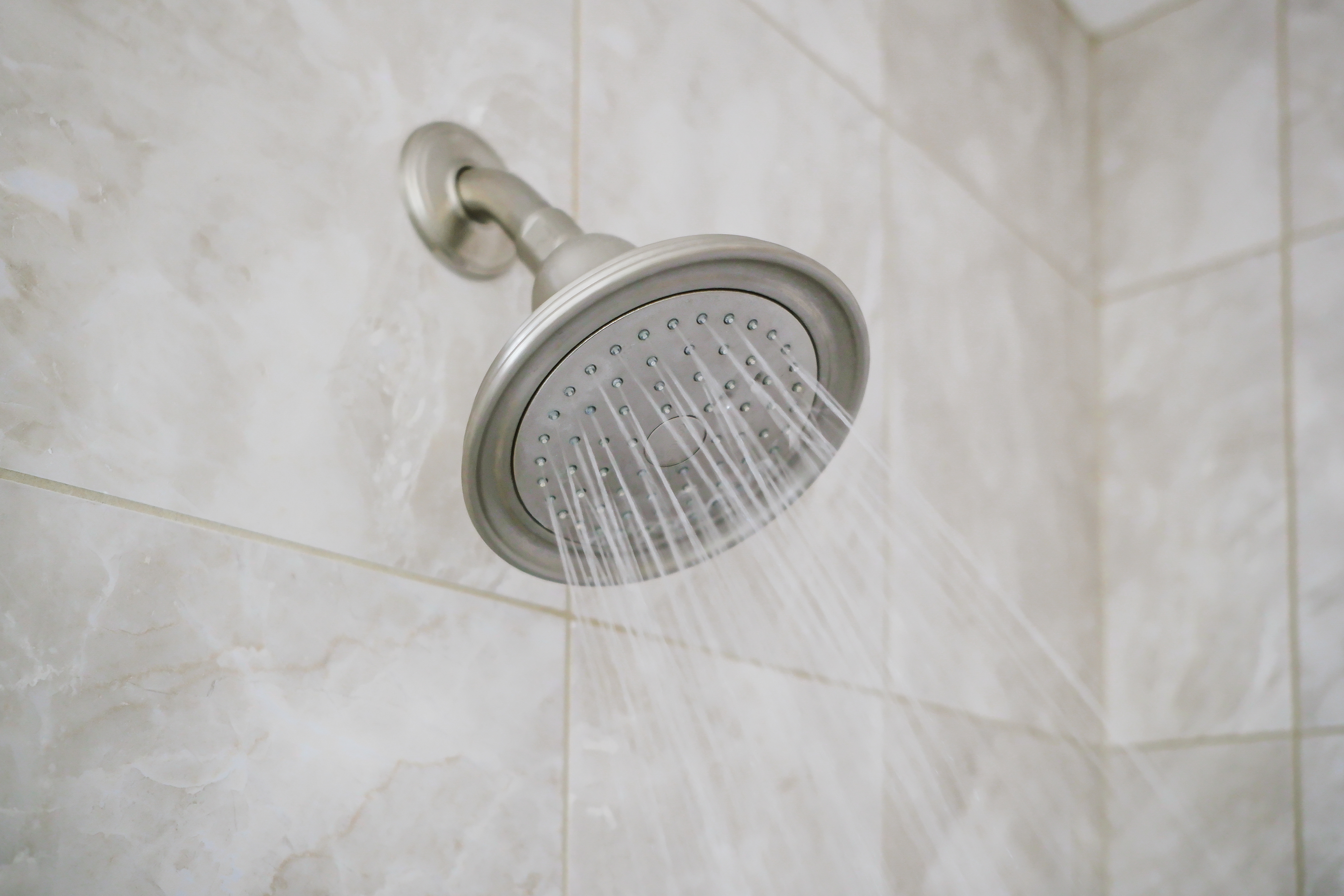 Shower head mounted to the wall with gray tiles 