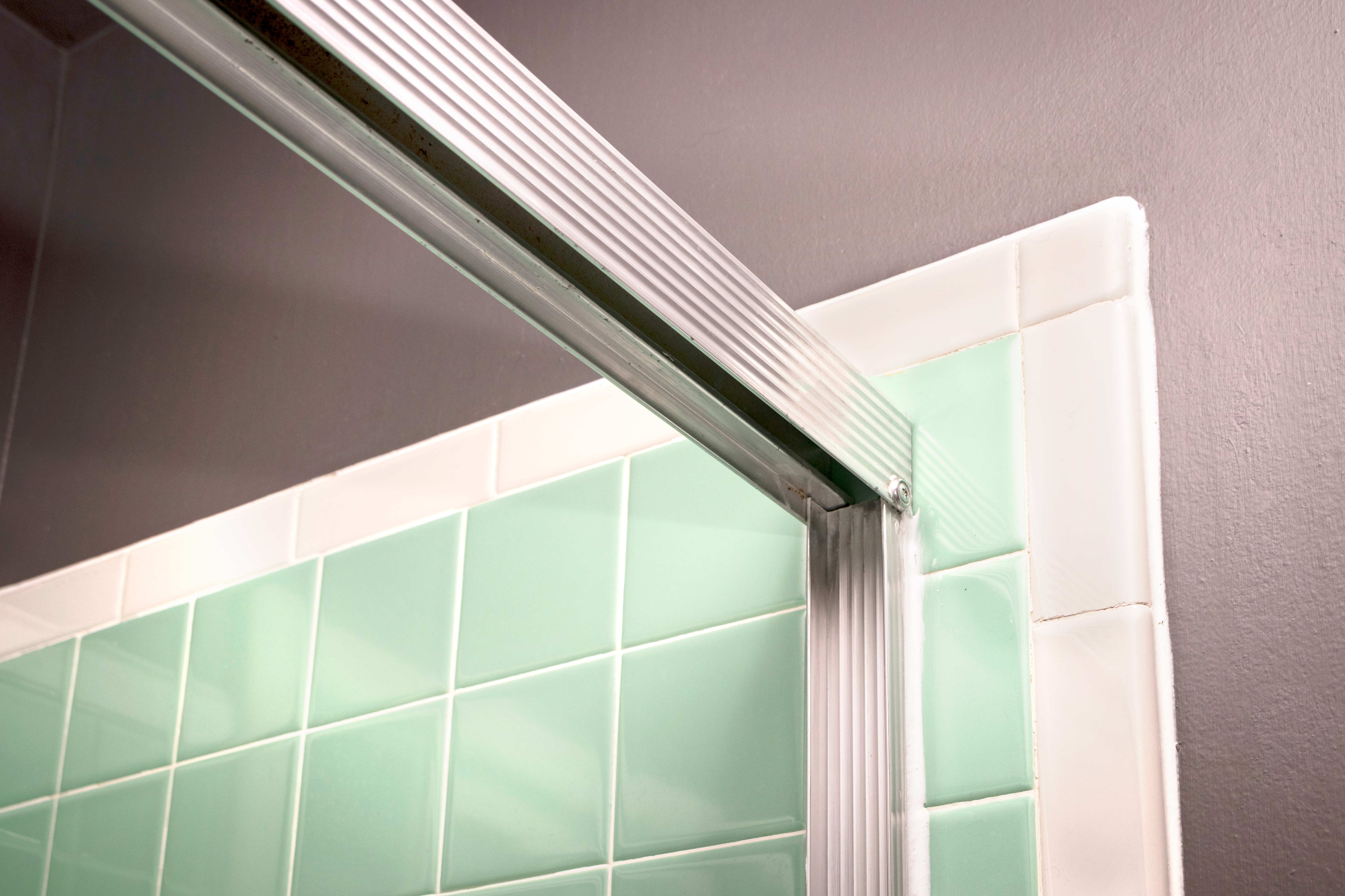 Shower door frame header attached to the wall