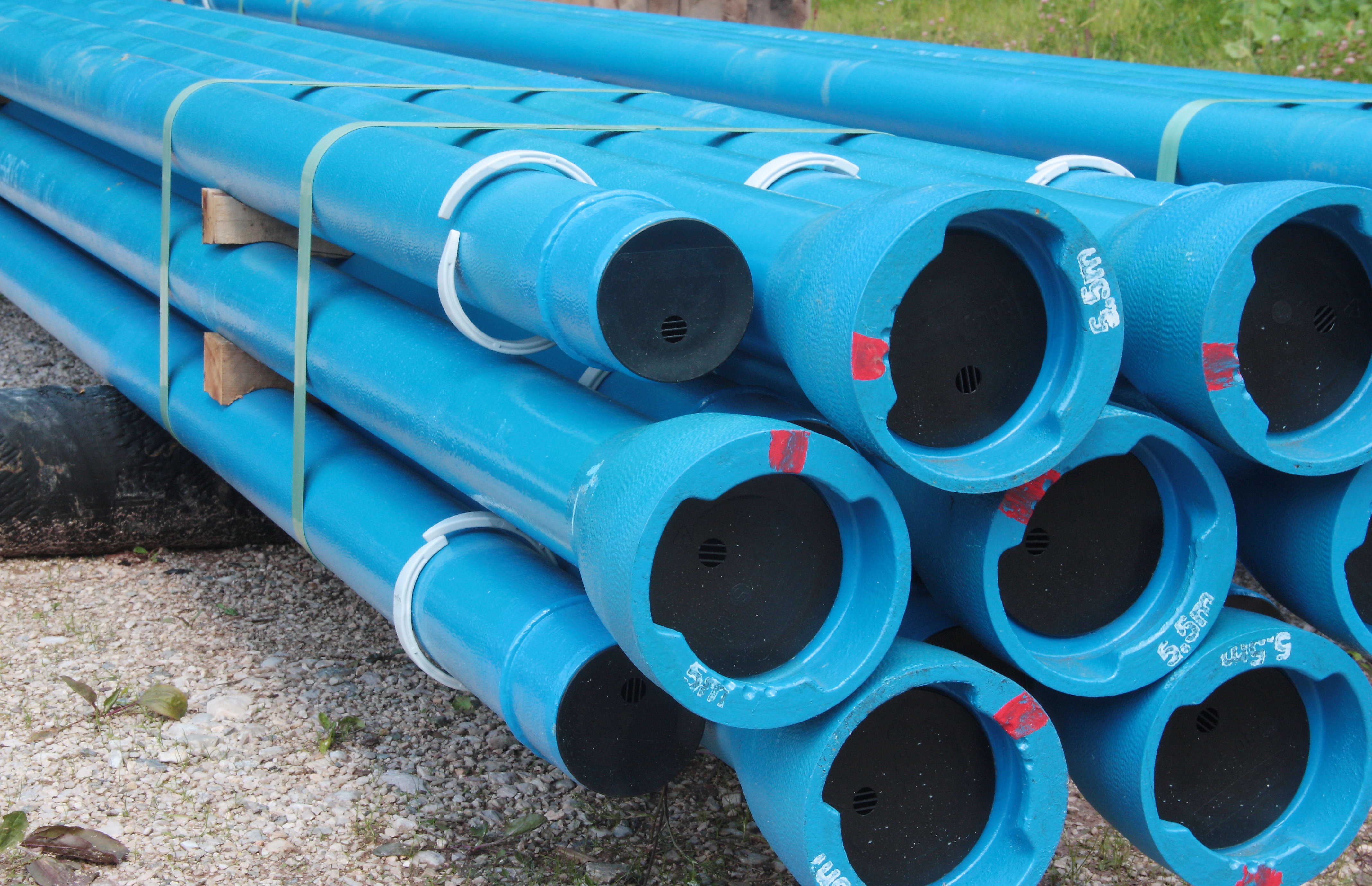 Stack of new PVC water main pipes in the yard