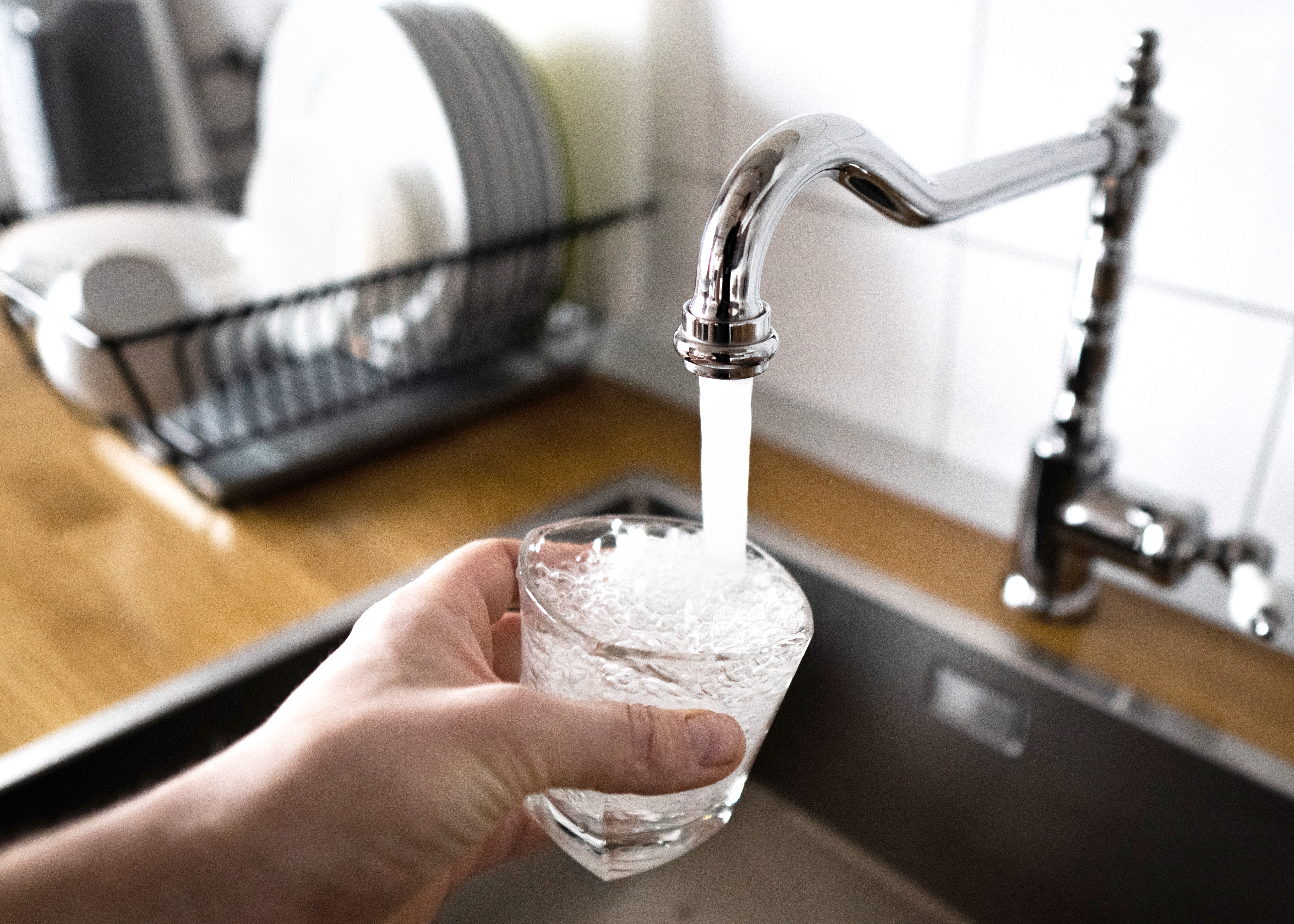 Person filling up a glass with tap water
