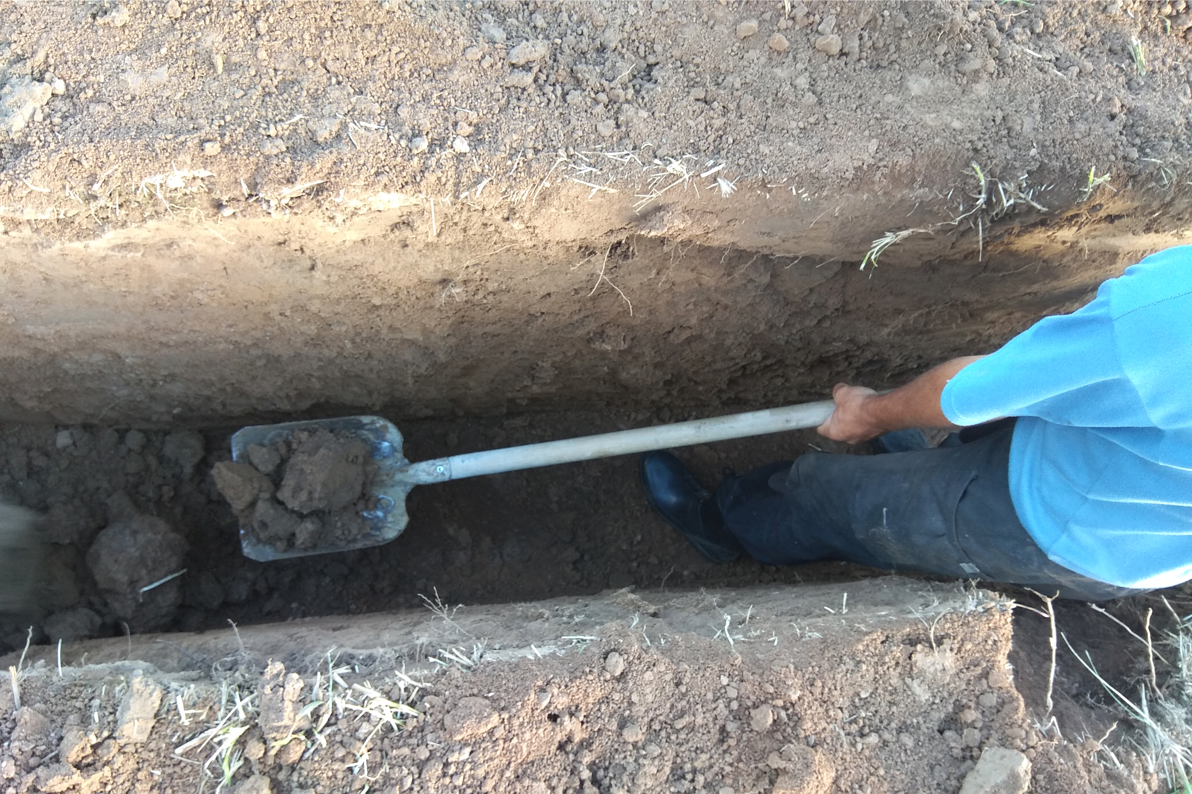 Worker excavating a deep trench for the main water line