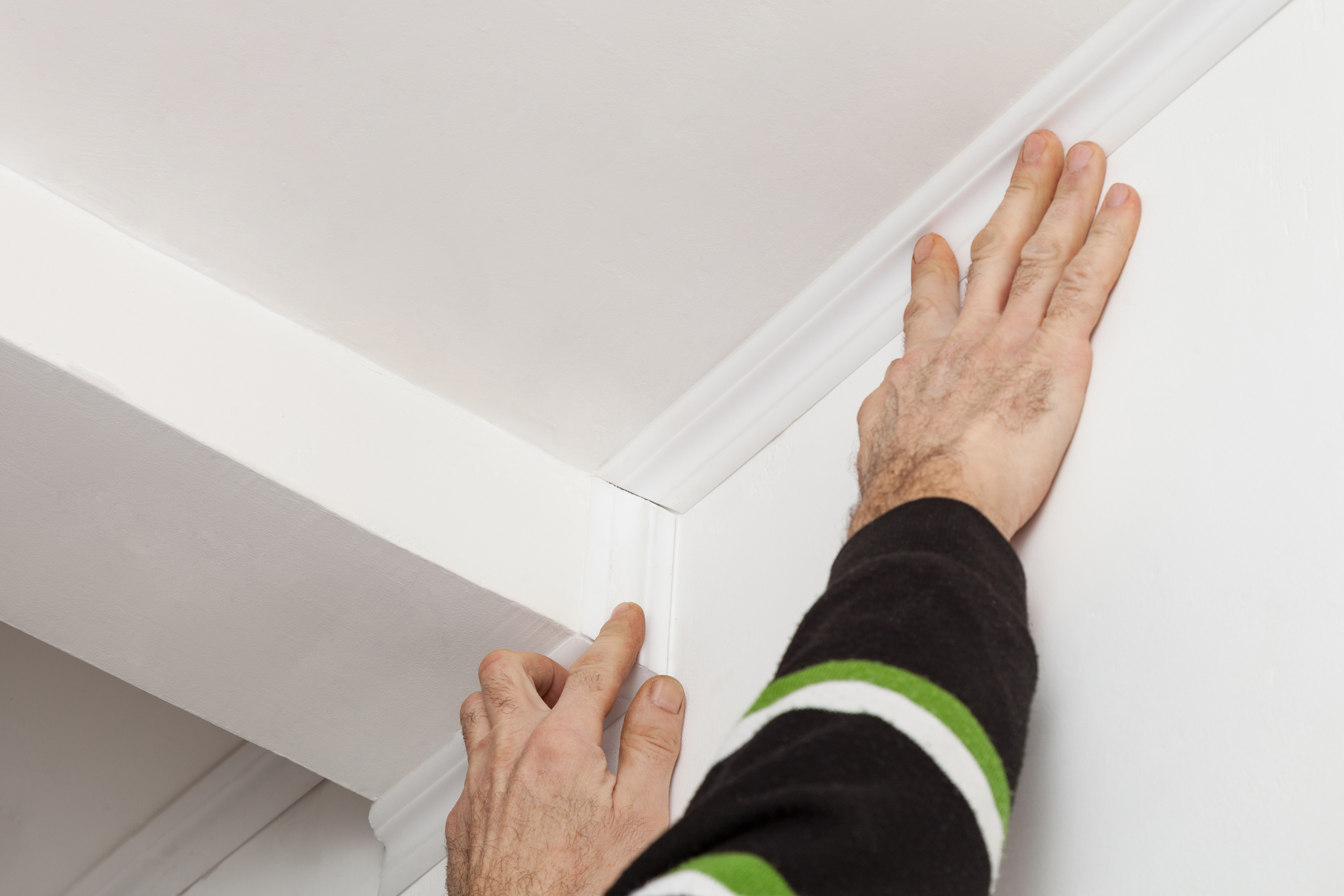 A person installing a foam crown molding 