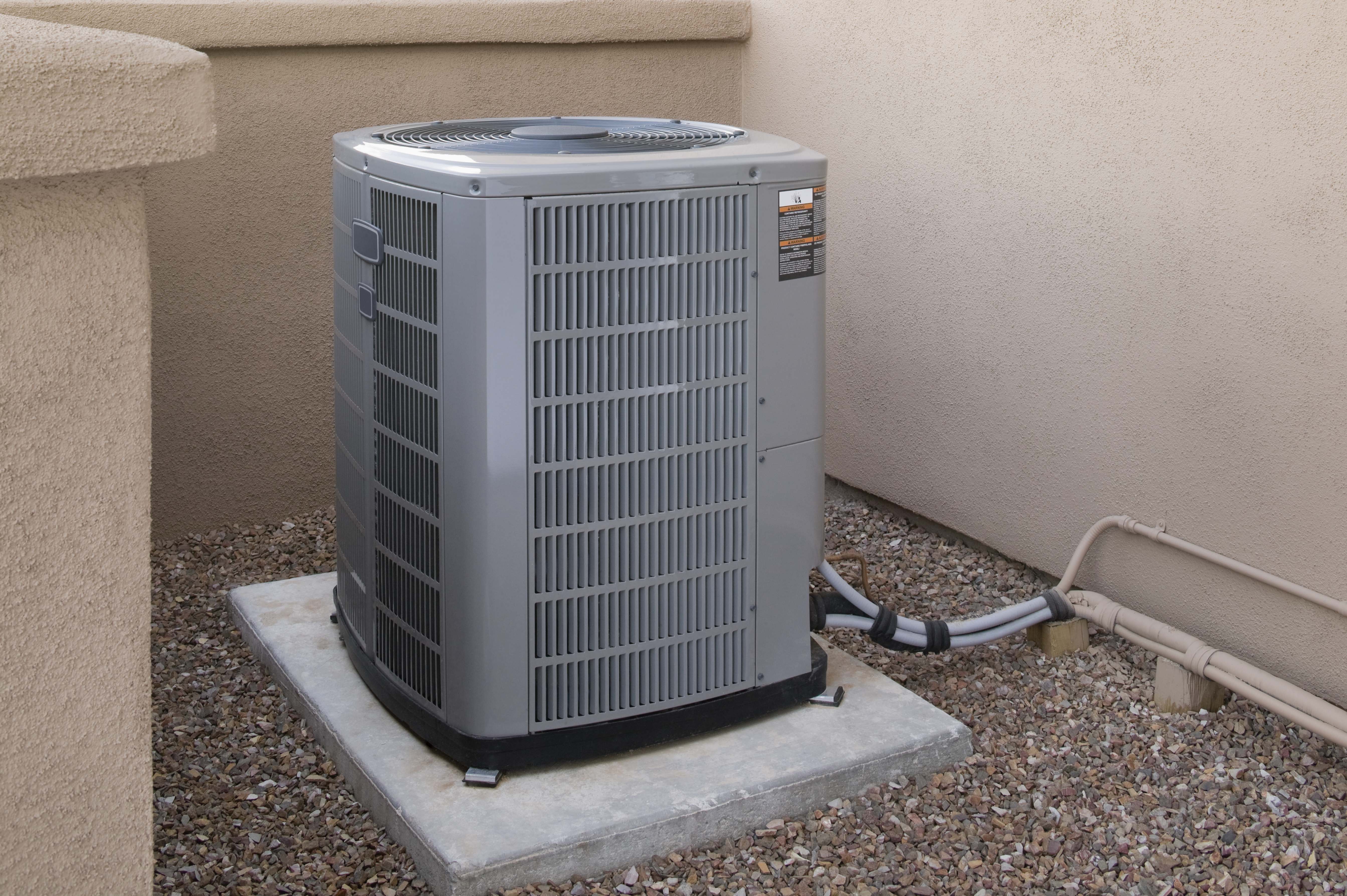 Central AC unit sitting on a concrete slab  