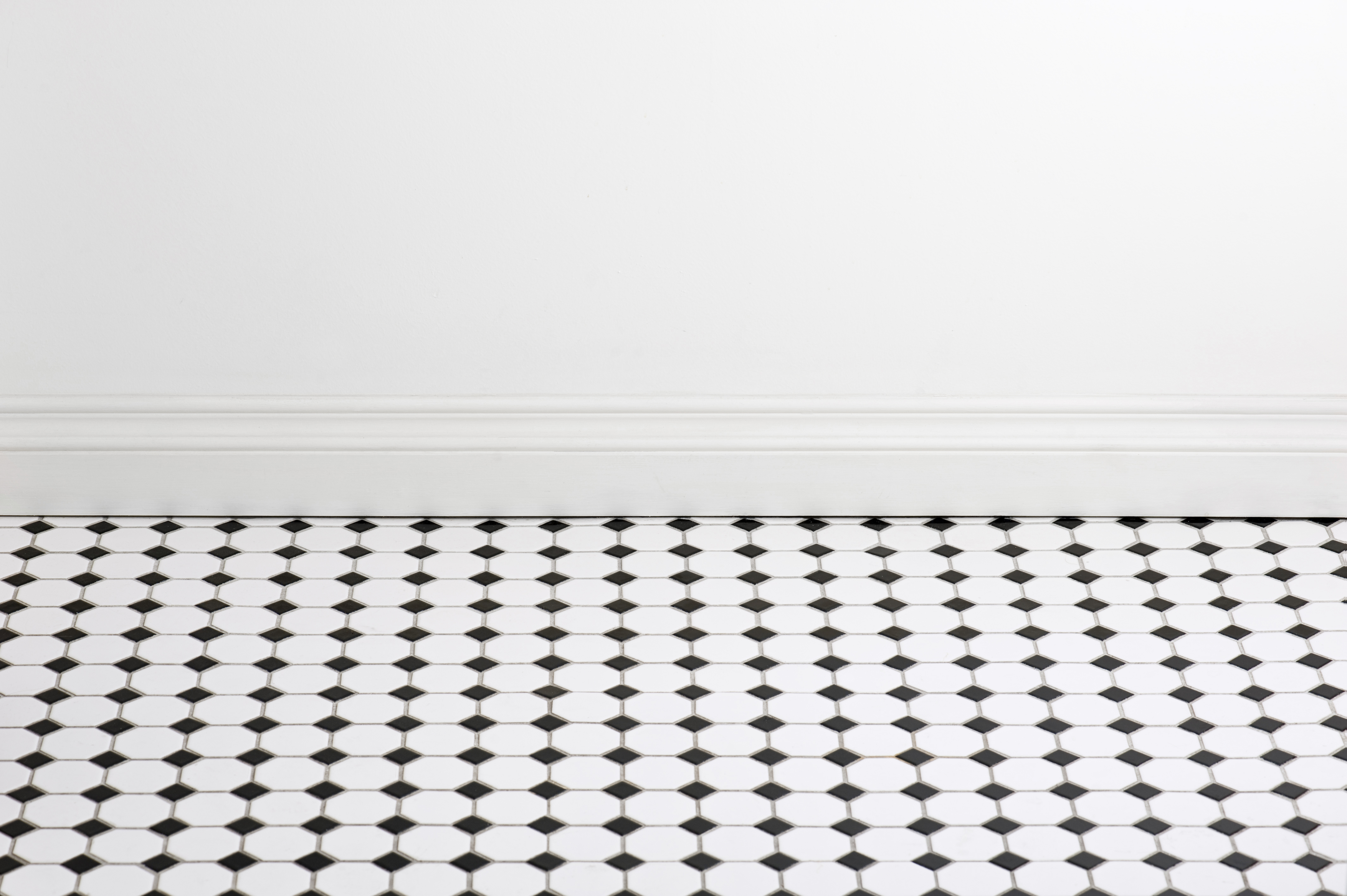 Bathroom with tile flooring and empty white wall 