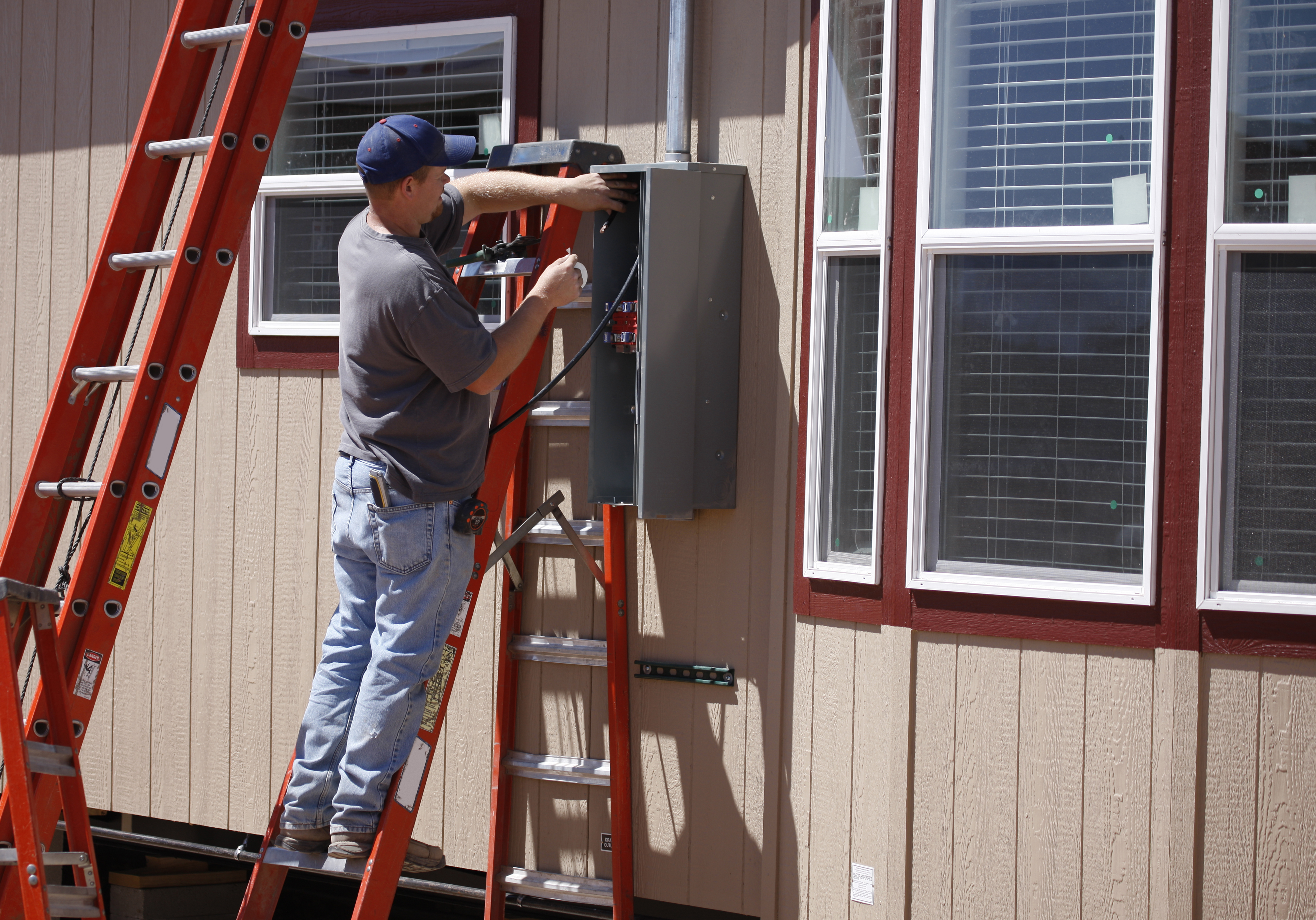 Electrician installing a new electrical box outside the house