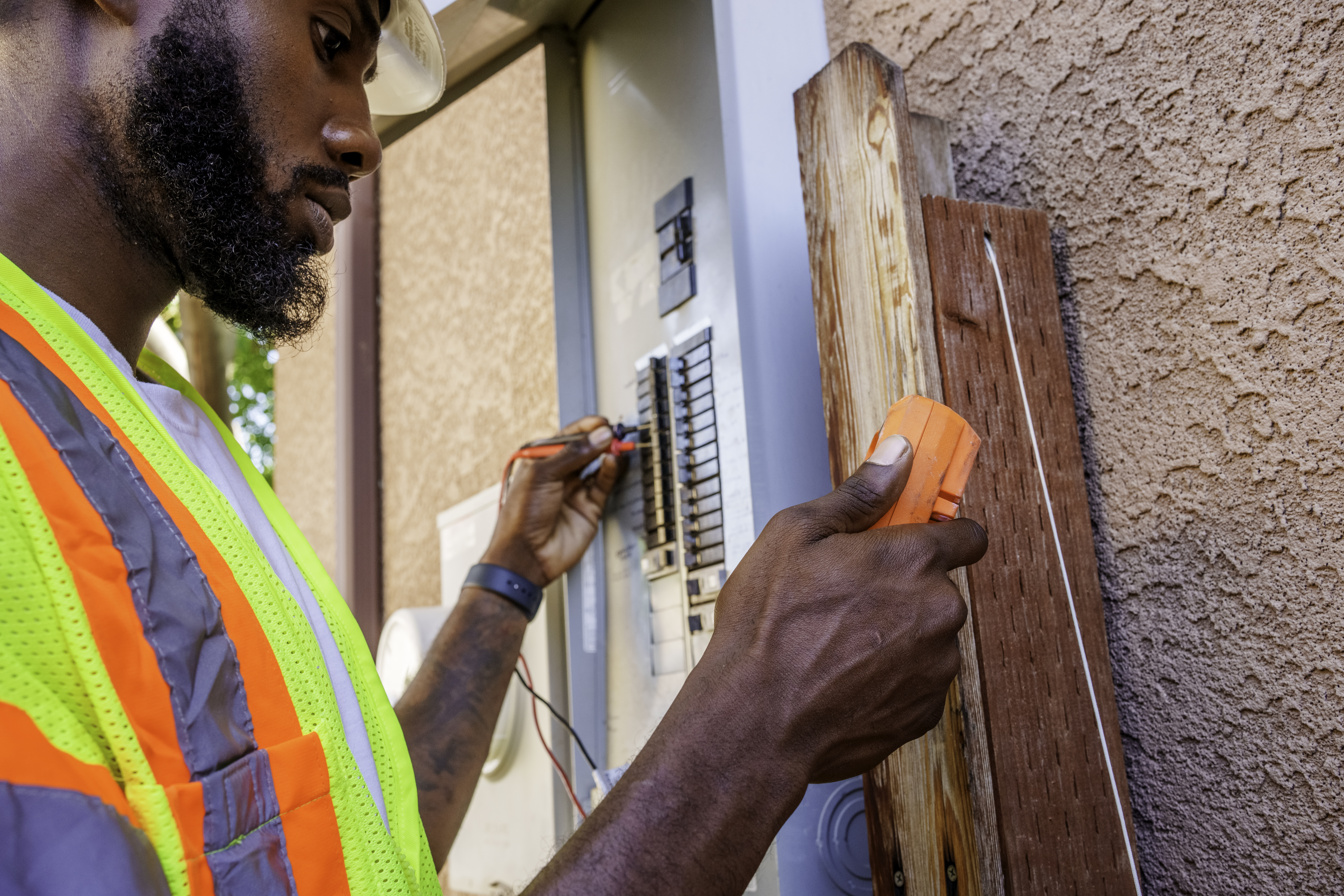 Electrician using a multimeter to test an electrical box