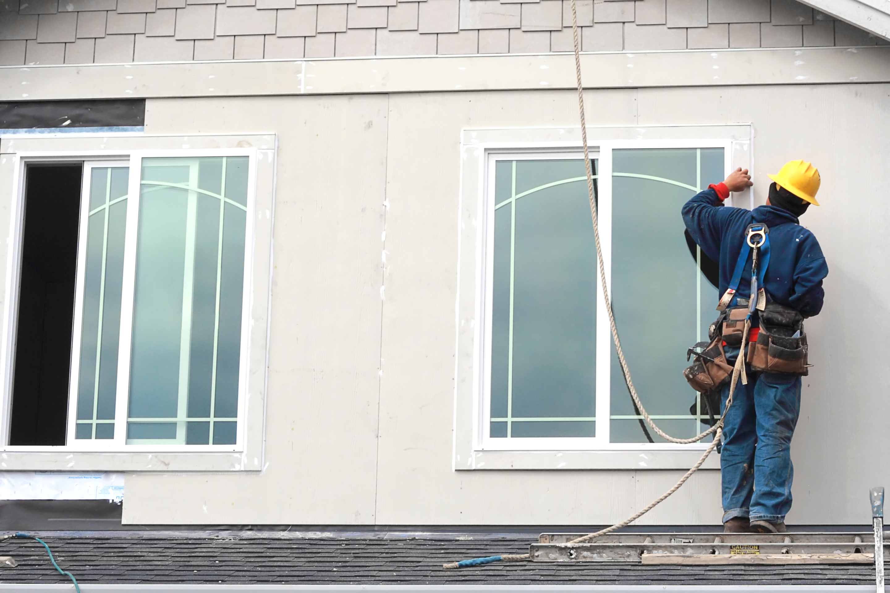 Contractor wearing a safety harness installing new windows