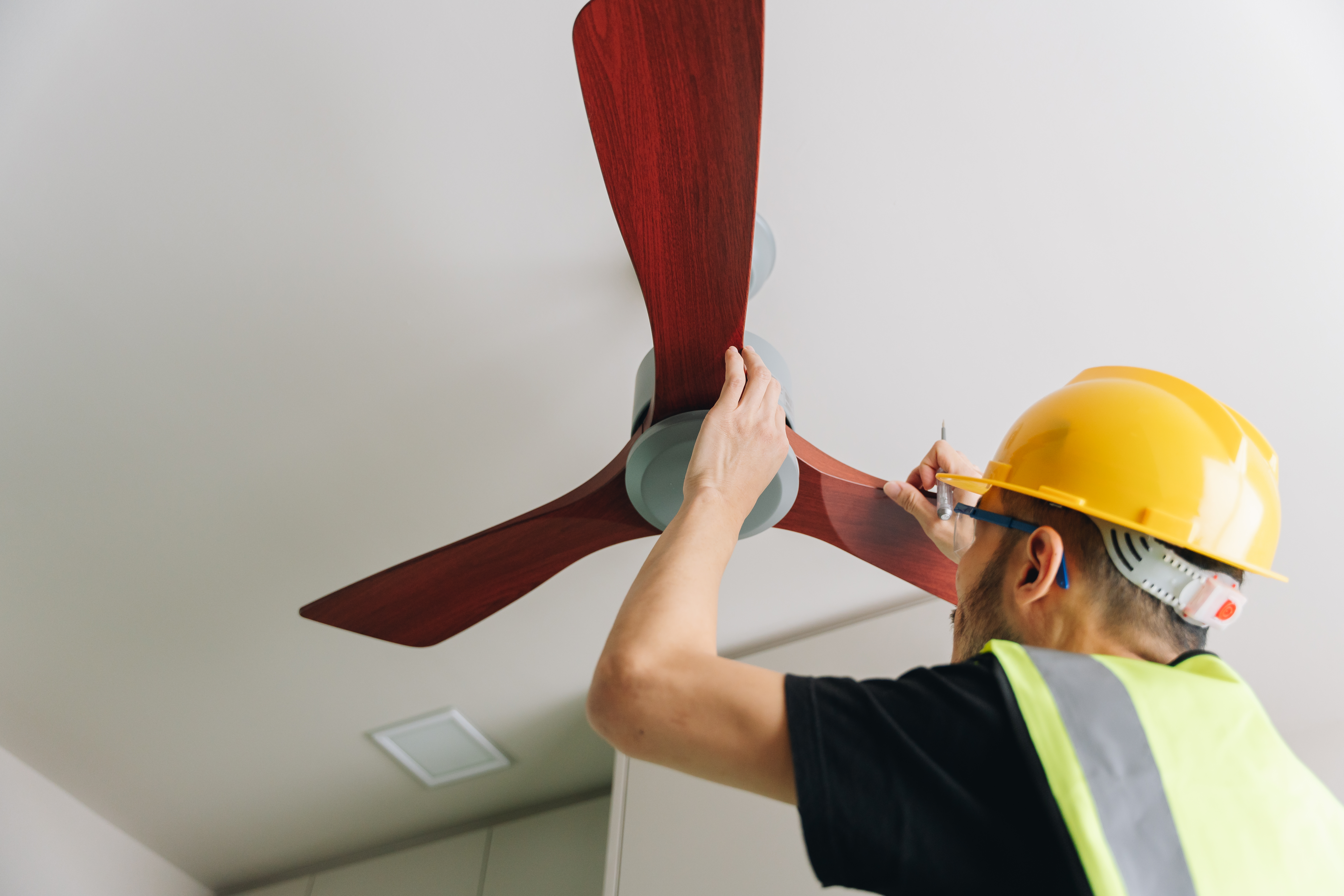 Technician installing wooden ceiling fan