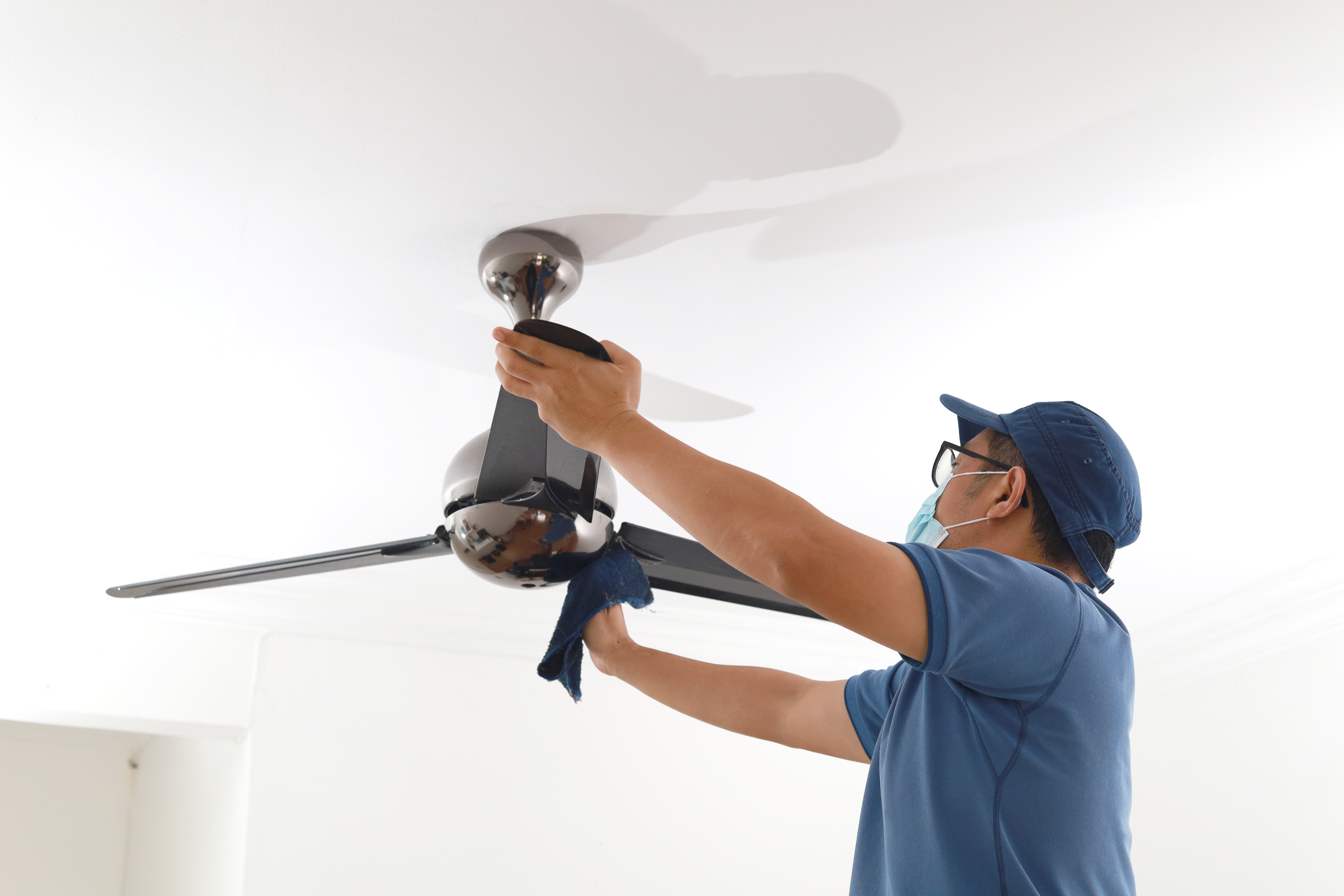 Man cleaning ceiling fan