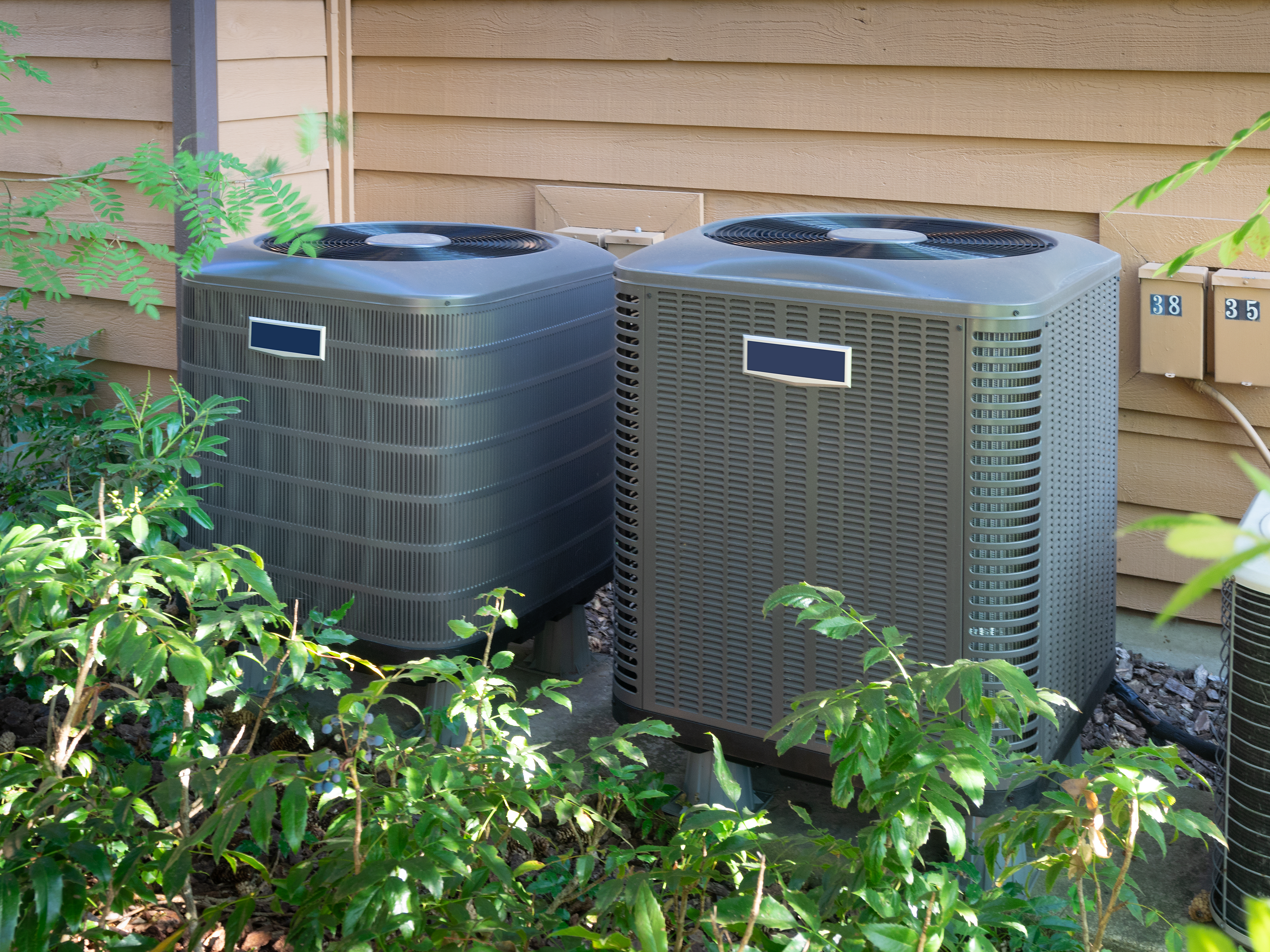 Two central air units outside an apartment complex