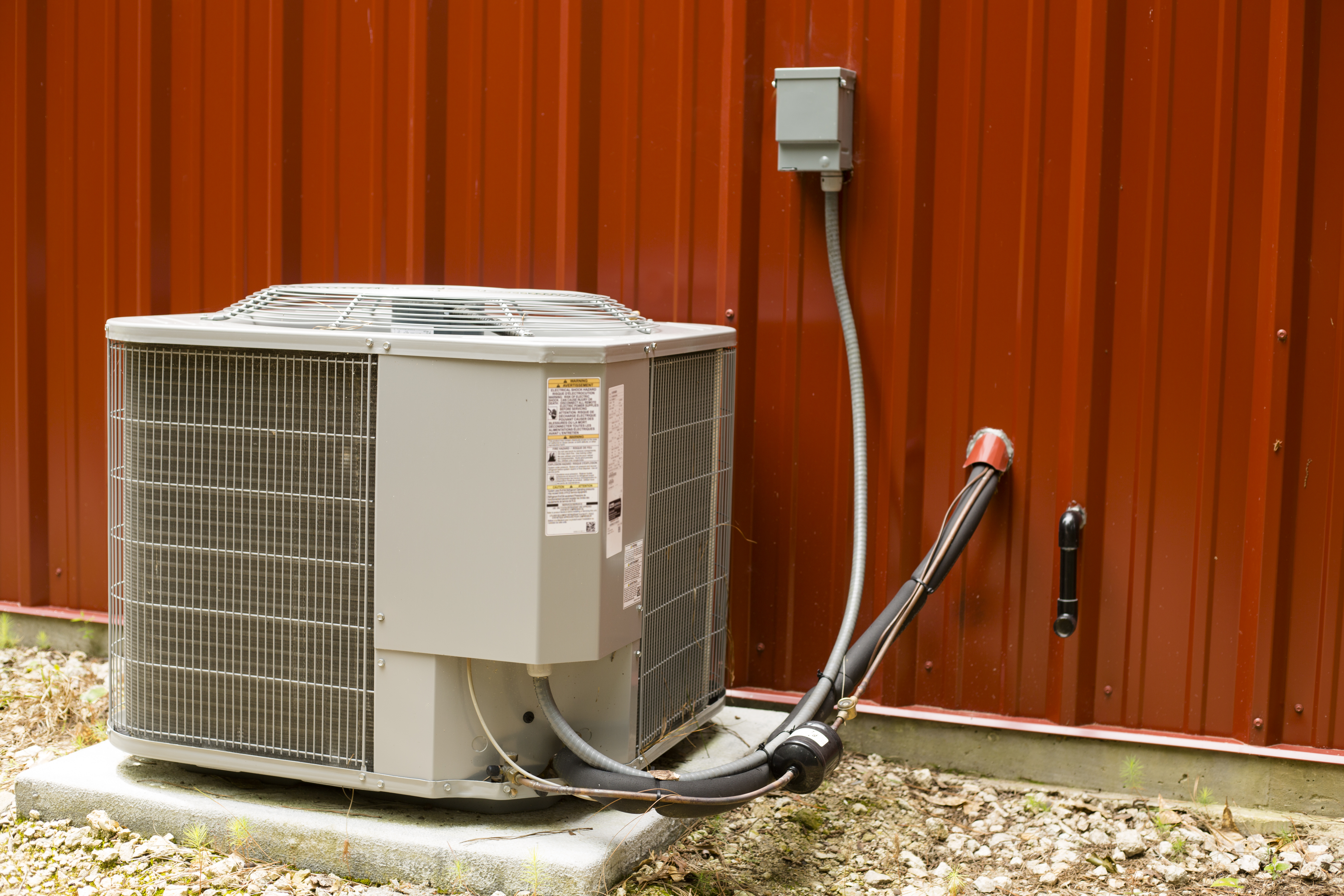 Outside Air conditioner unit beside red metal building