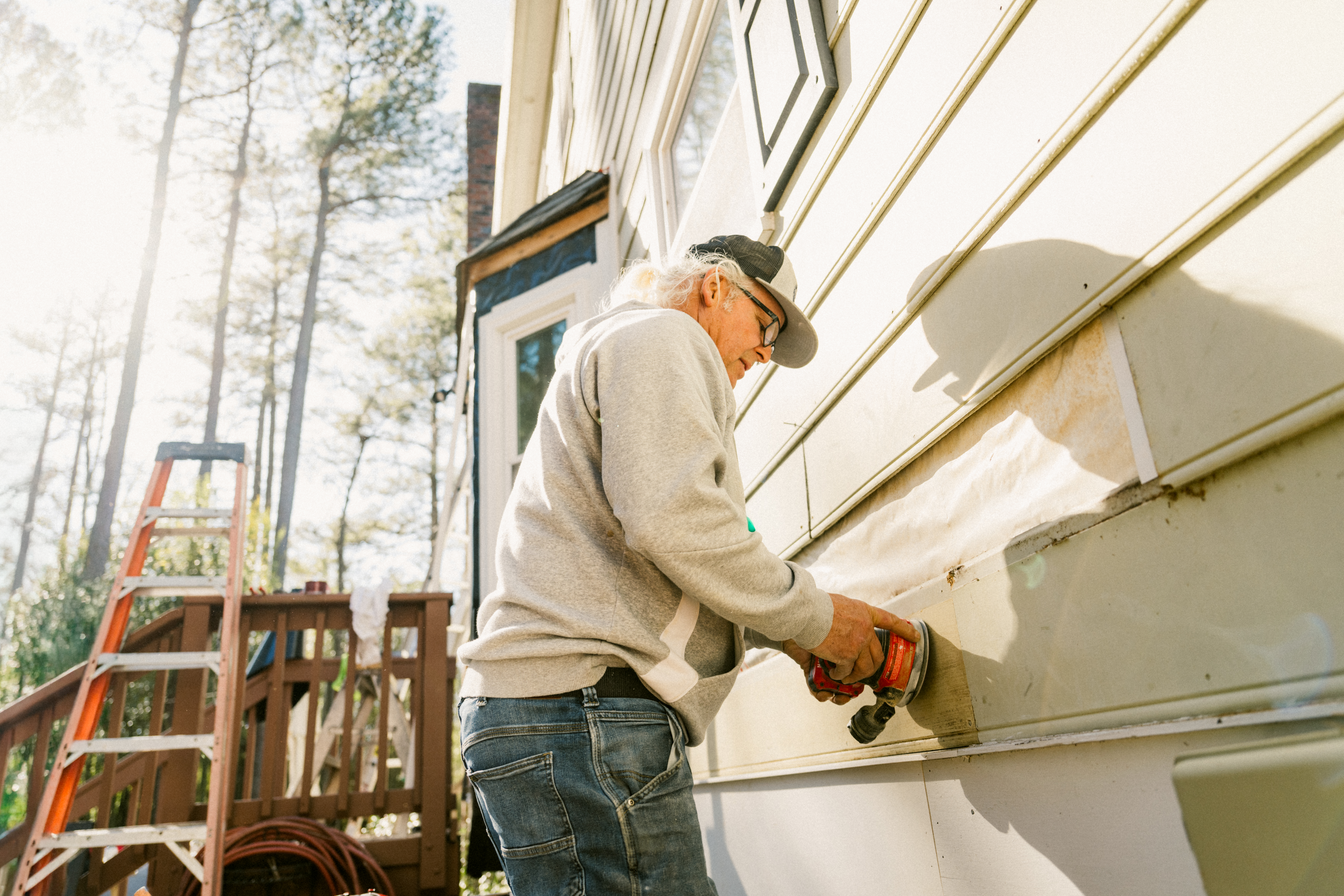 Contractor repairing siding on a colonial-style house
