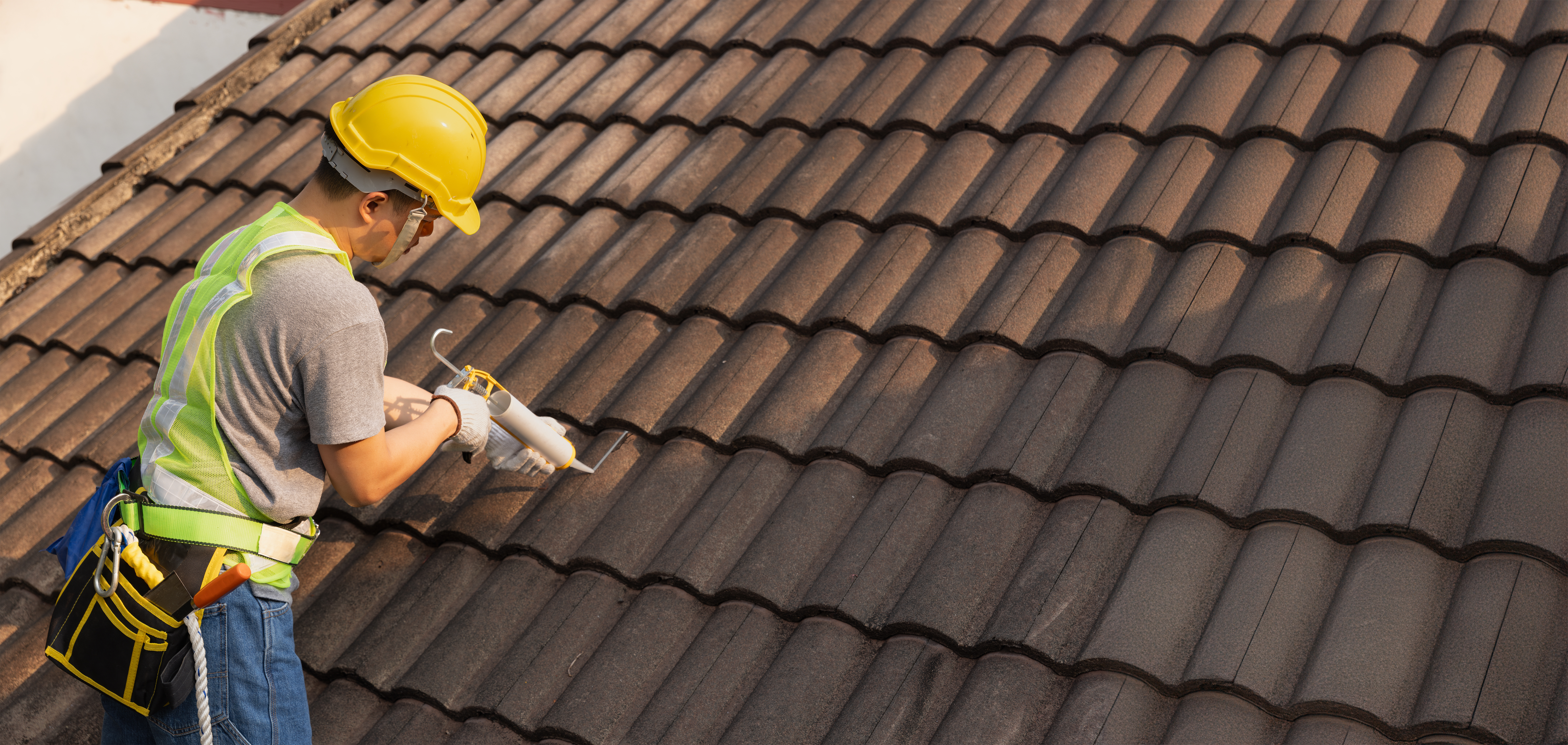 worker fixing cracked tile on roof