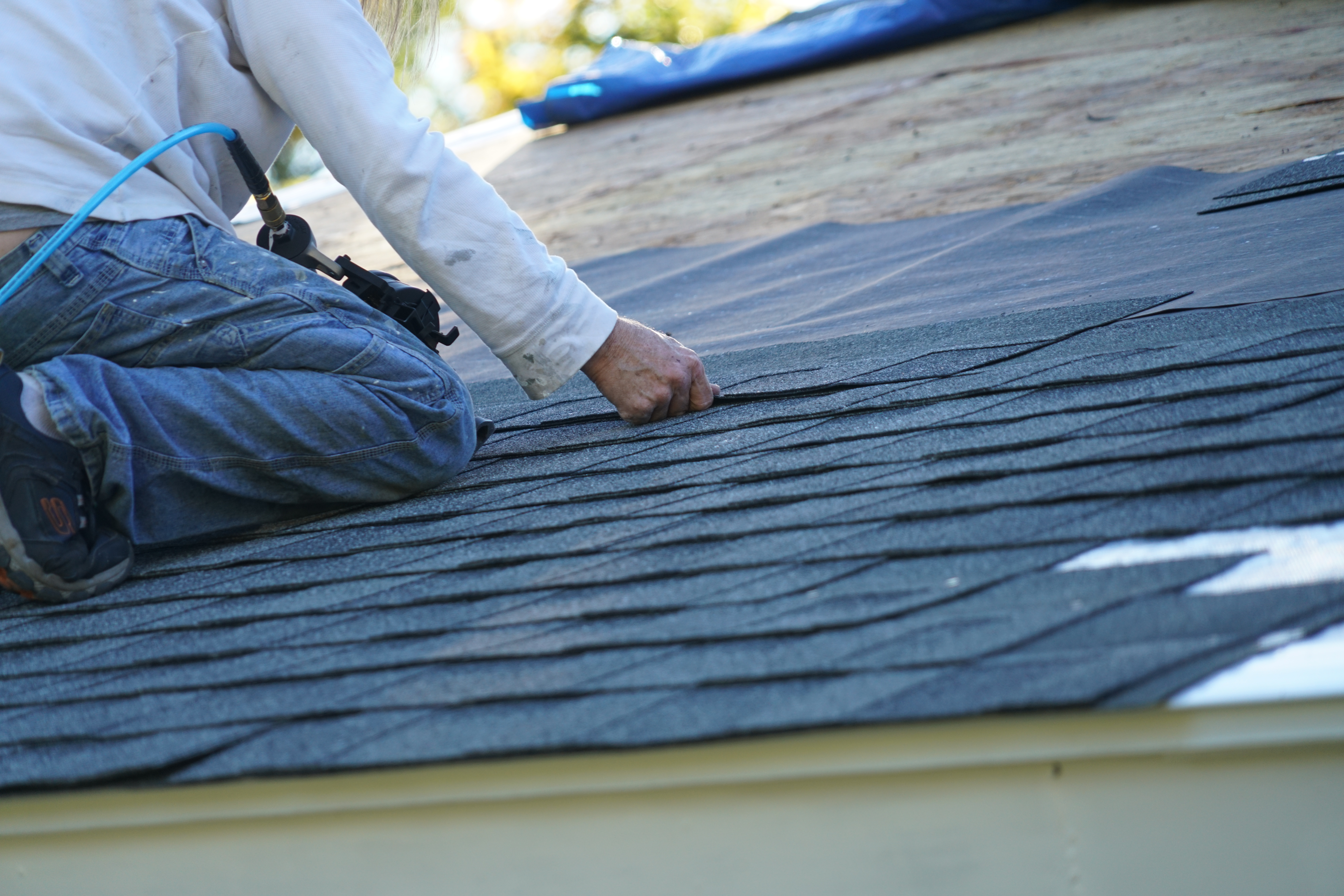 workman installing shingle on roof  