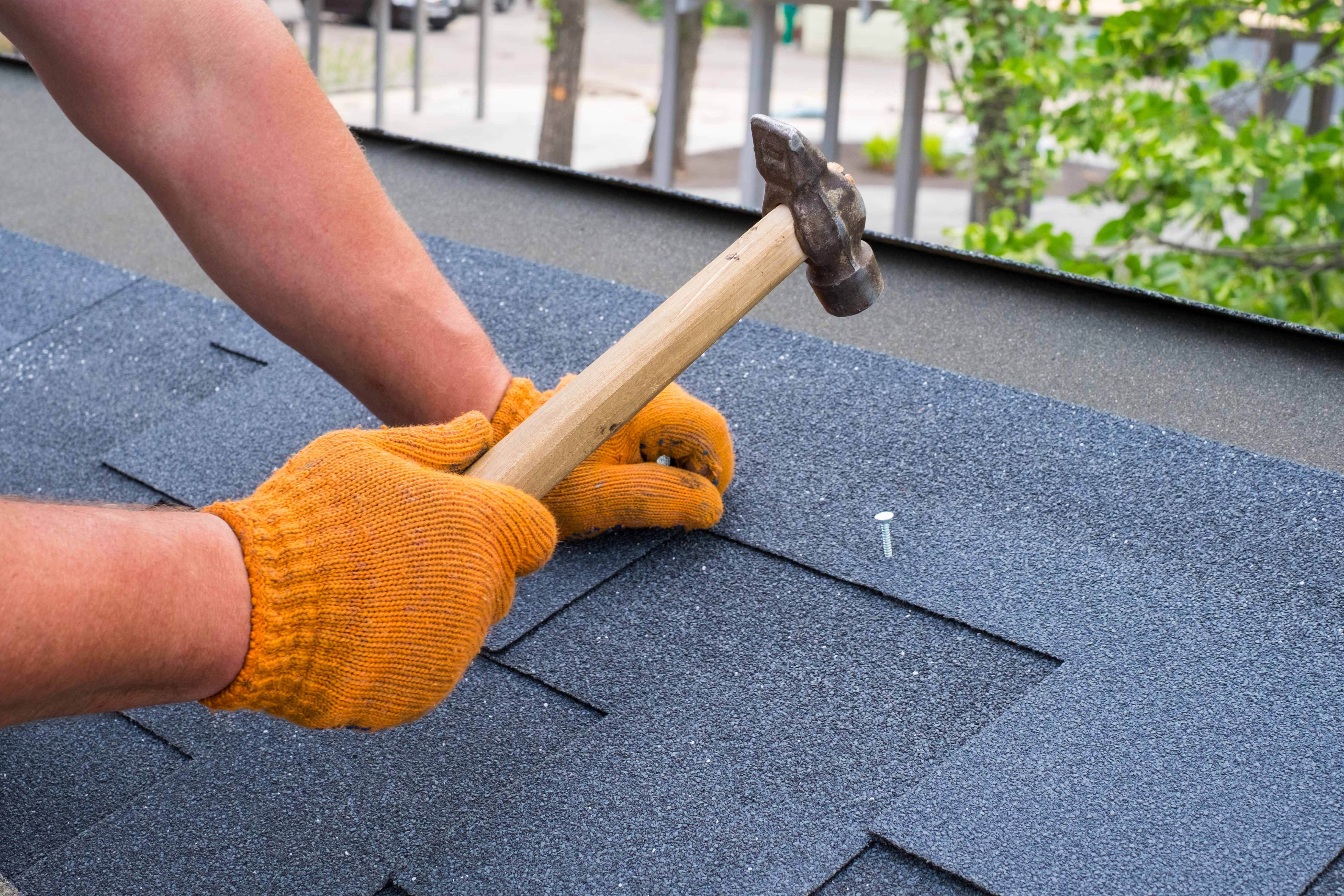 Roofer repairing an asphalt shingle roof