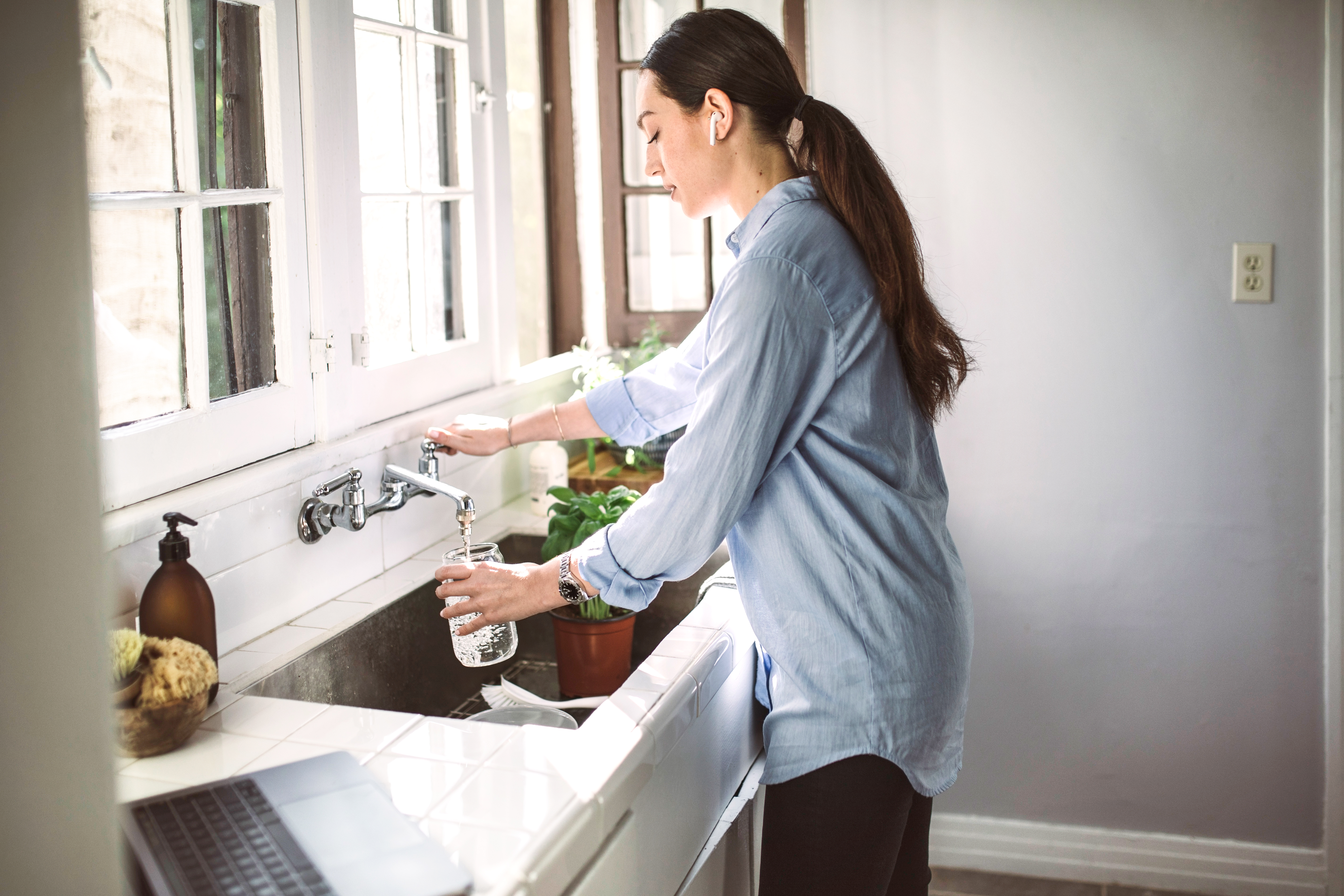 Woman in the kitchen filling up a jar with water