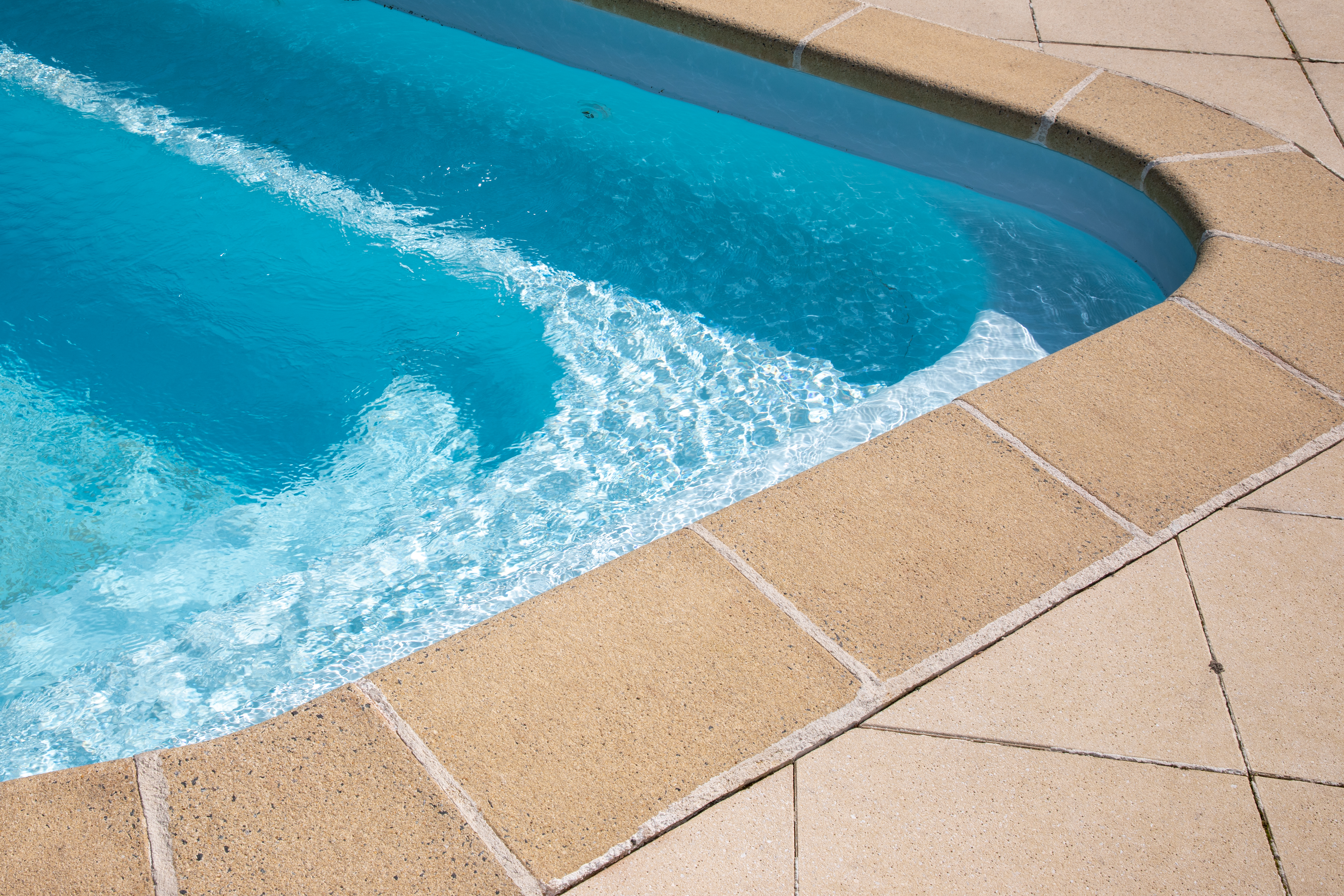 The corner of a pool with visible pool liner and stairs to descend