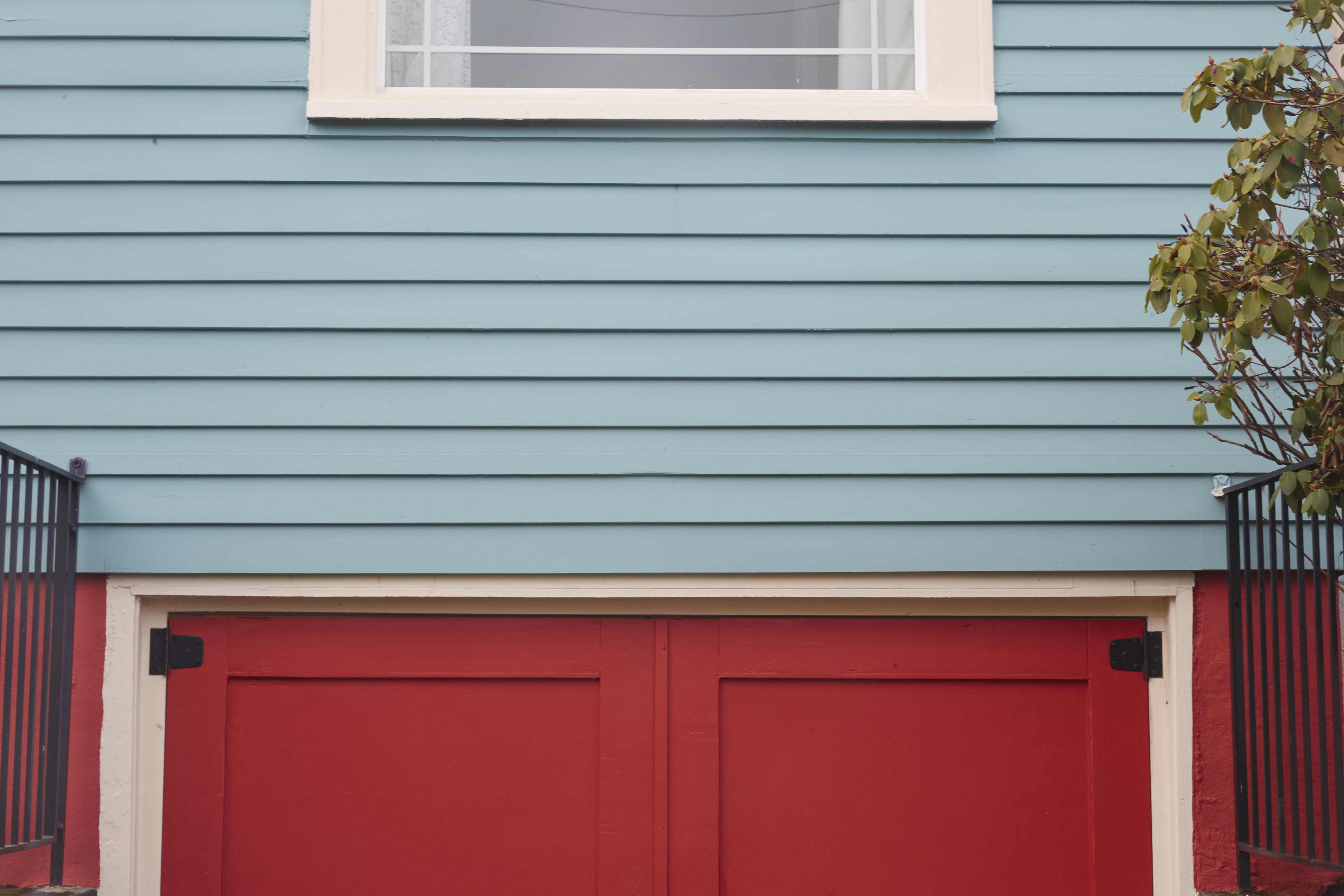 A blue wooden siding over a red door