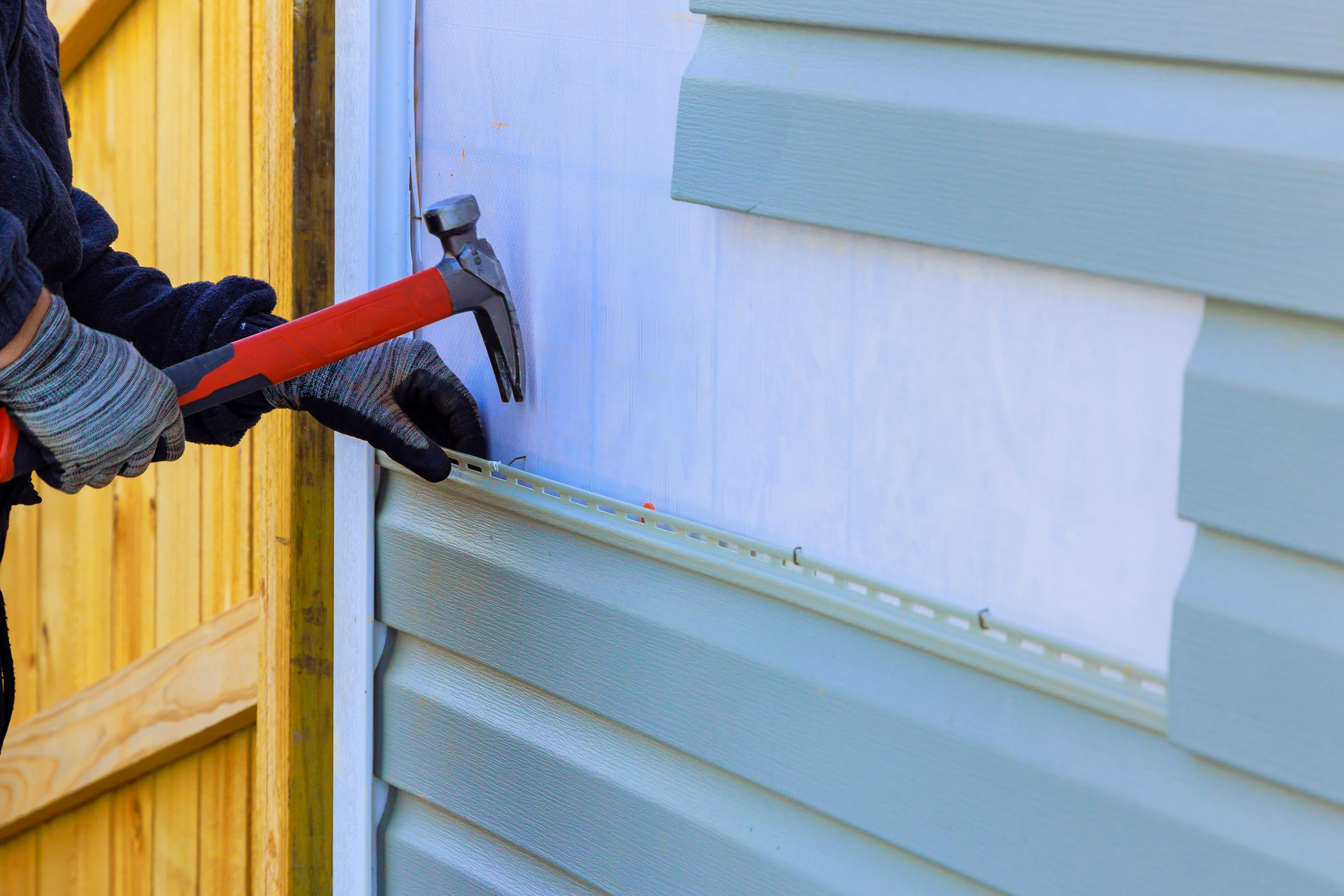 A person replacing vinyl siding