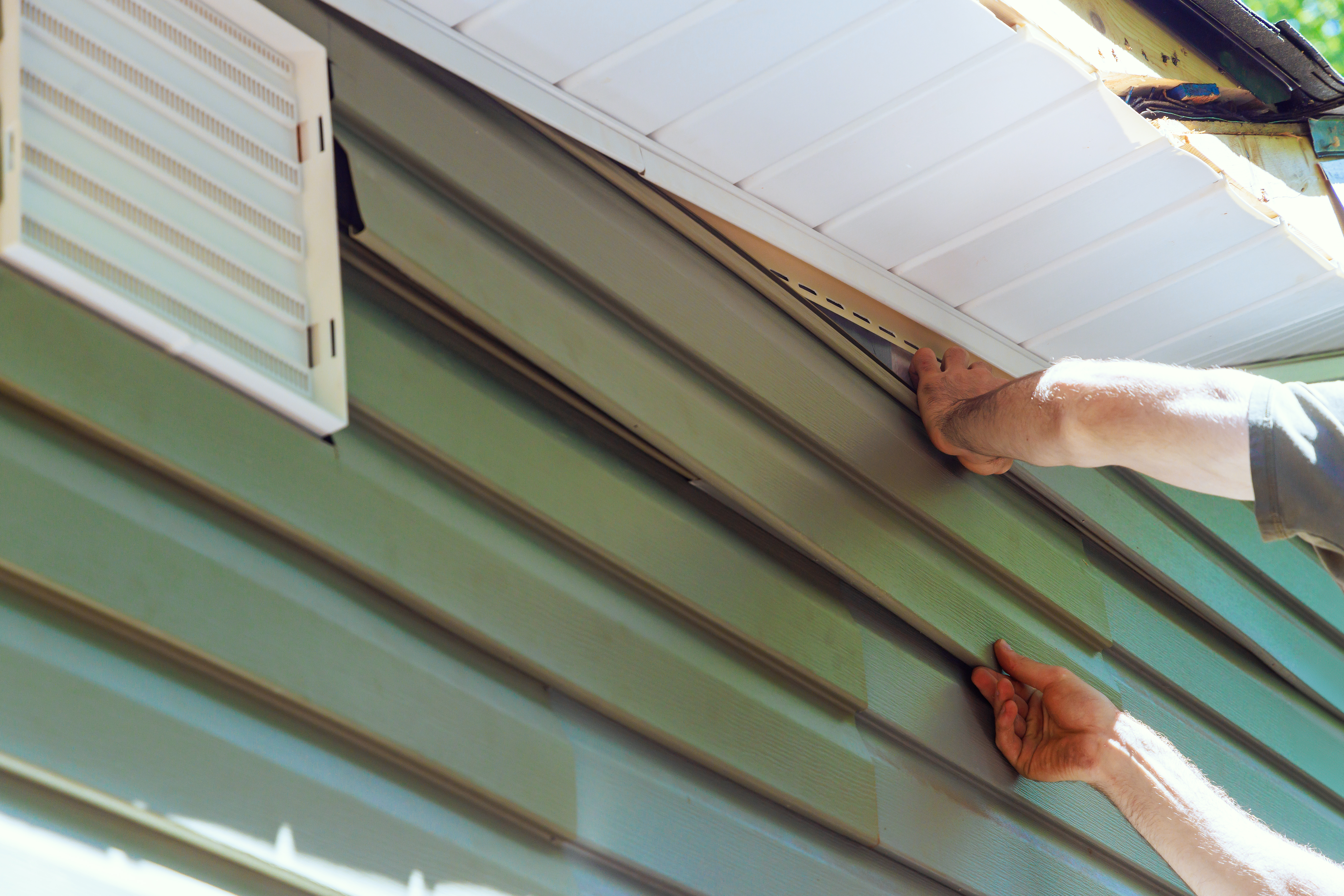 Worker installing vinyl plastic siding panels 