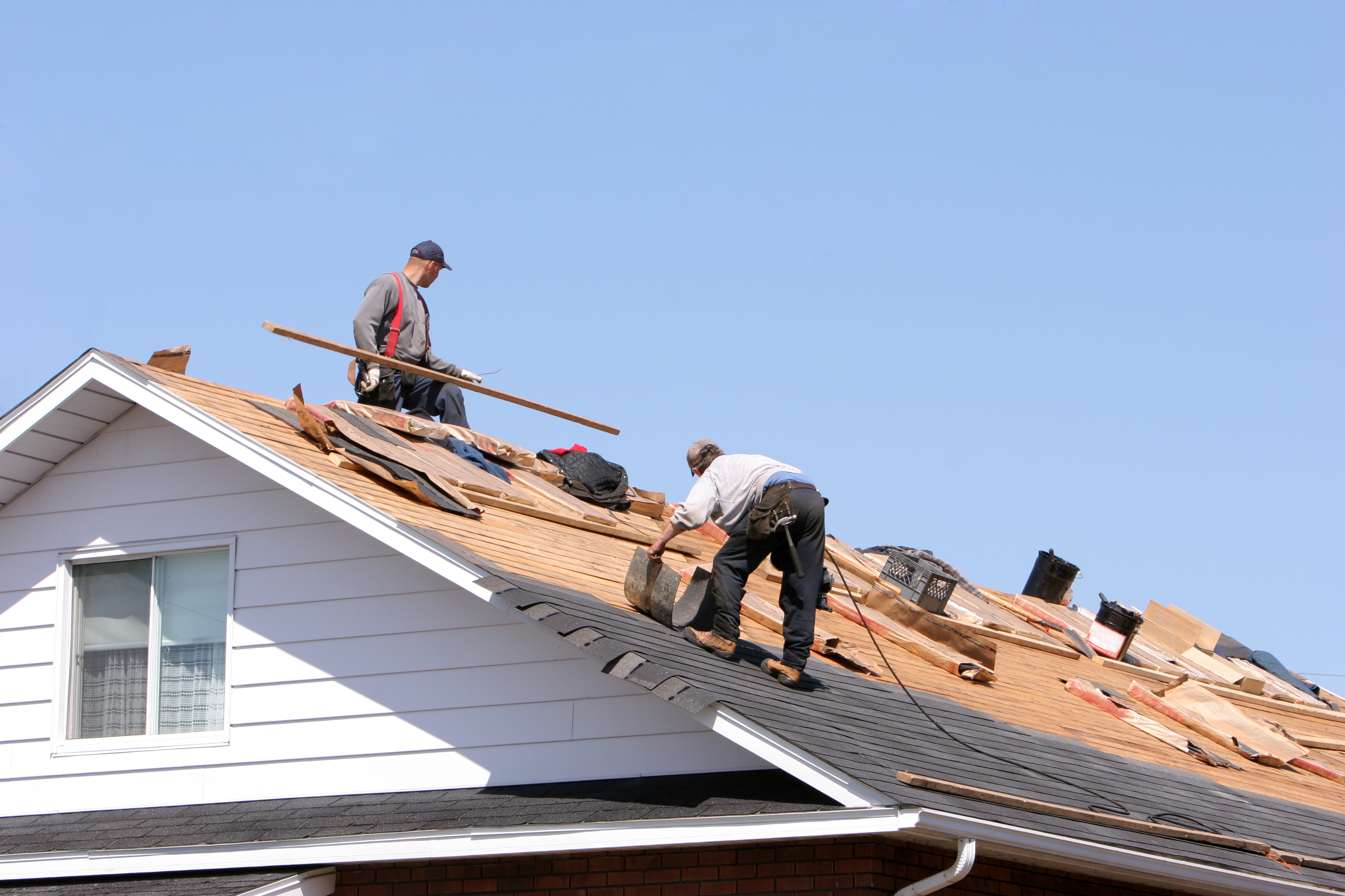 Workers installing a new asphalt shingle roof on a house