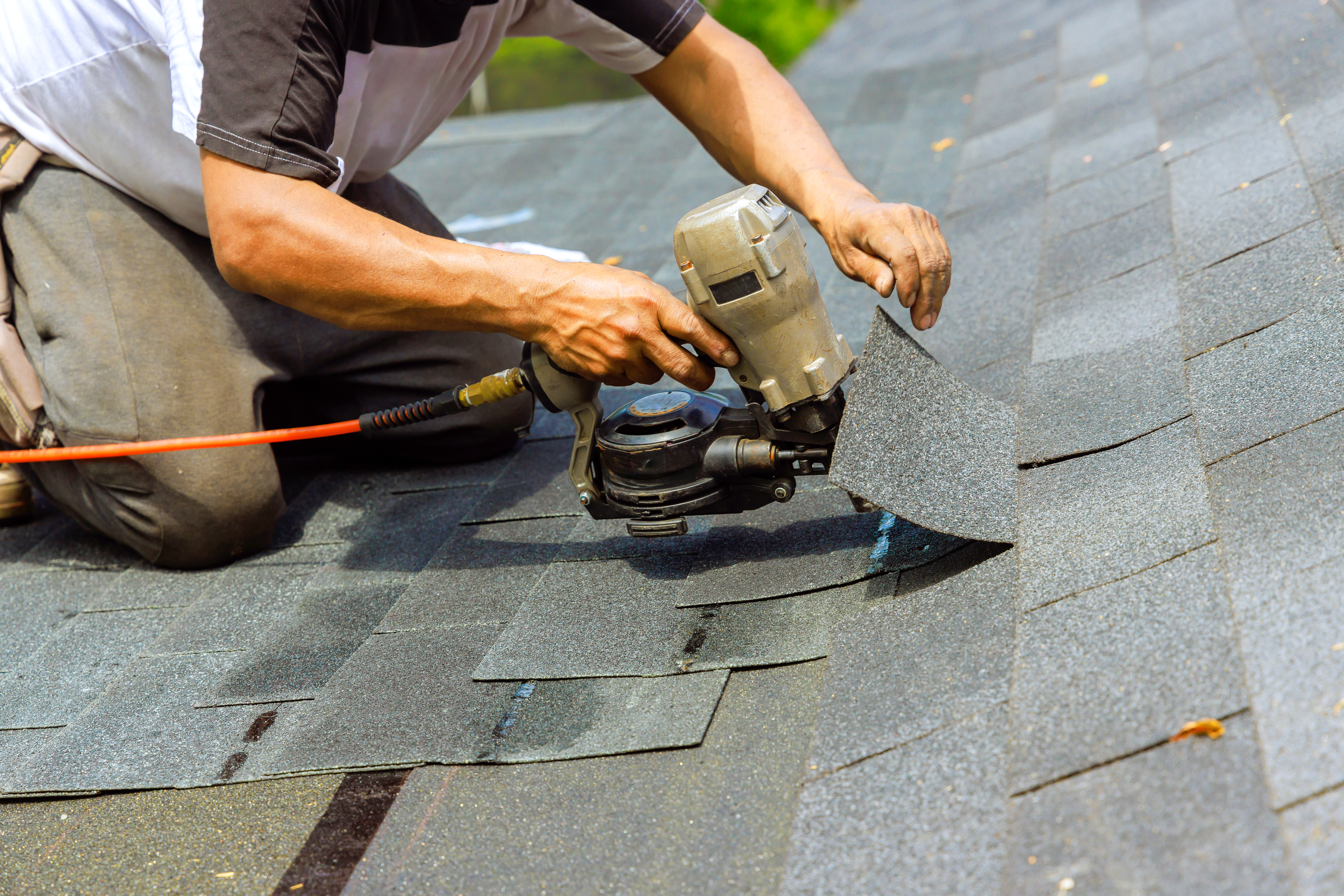 A roofing contractor using a nail gun 