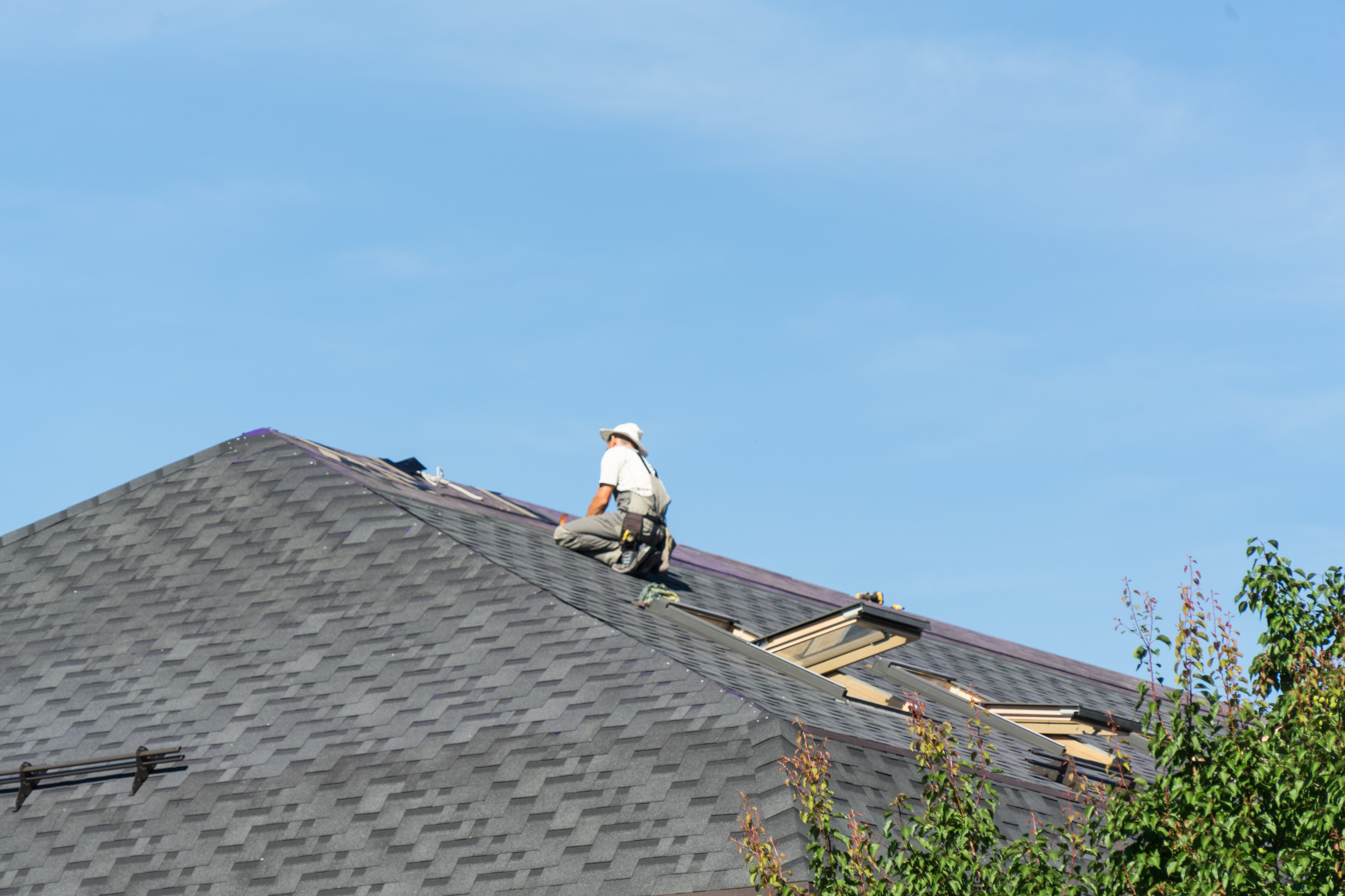 Roofer repairing a large asphalt shingle roof