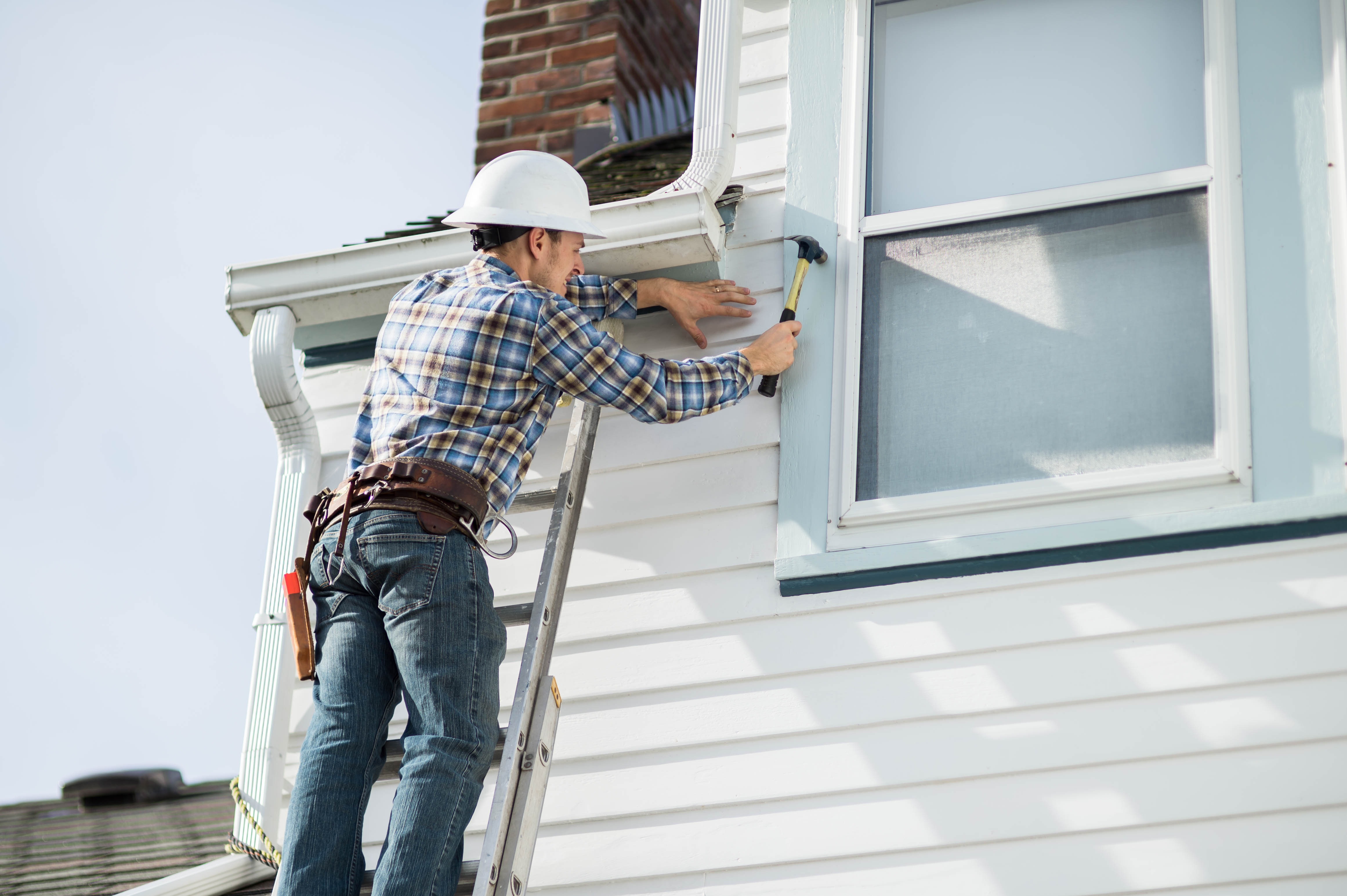 A construction worker installing new siding panels