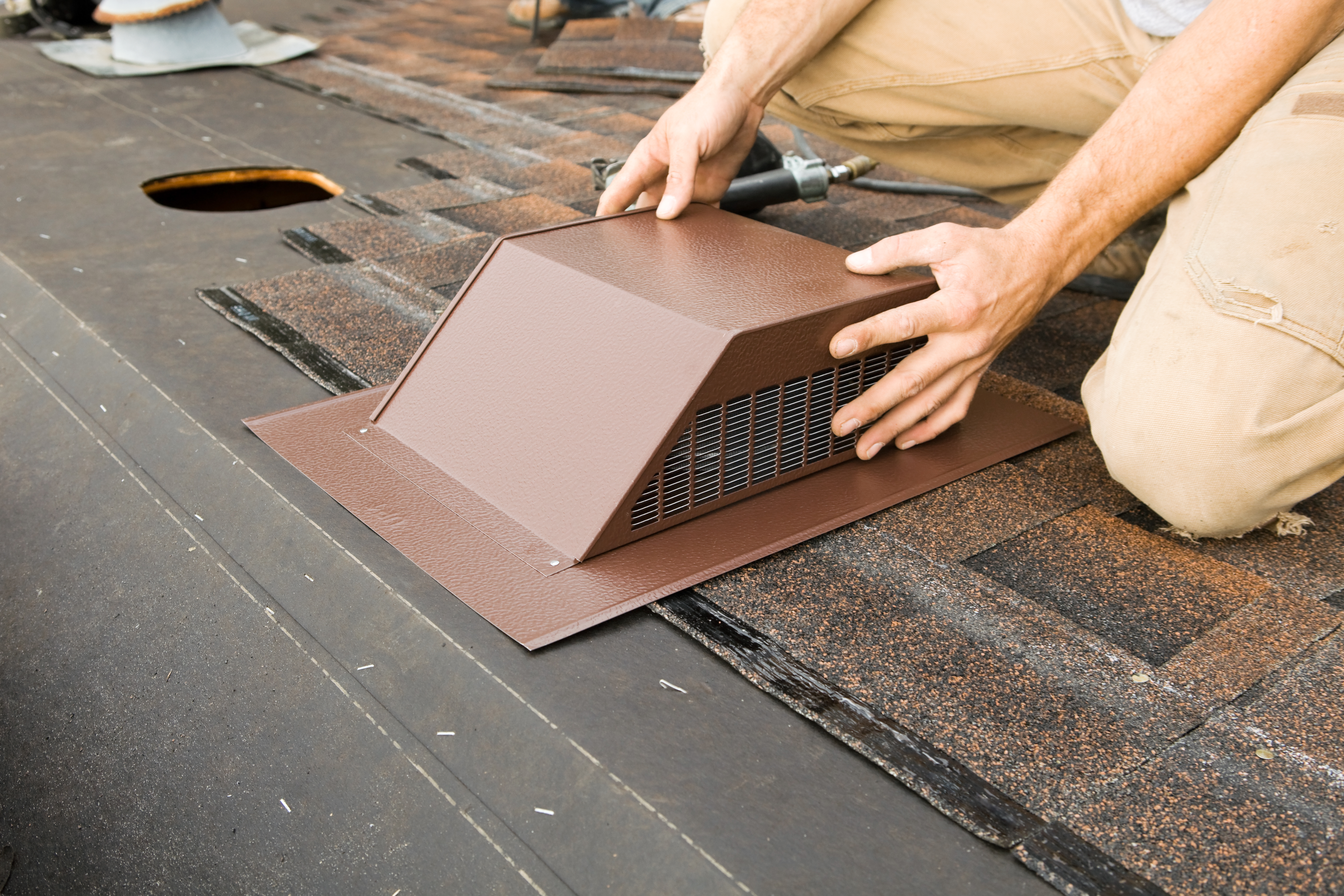 Worker installing attic vent on the roof