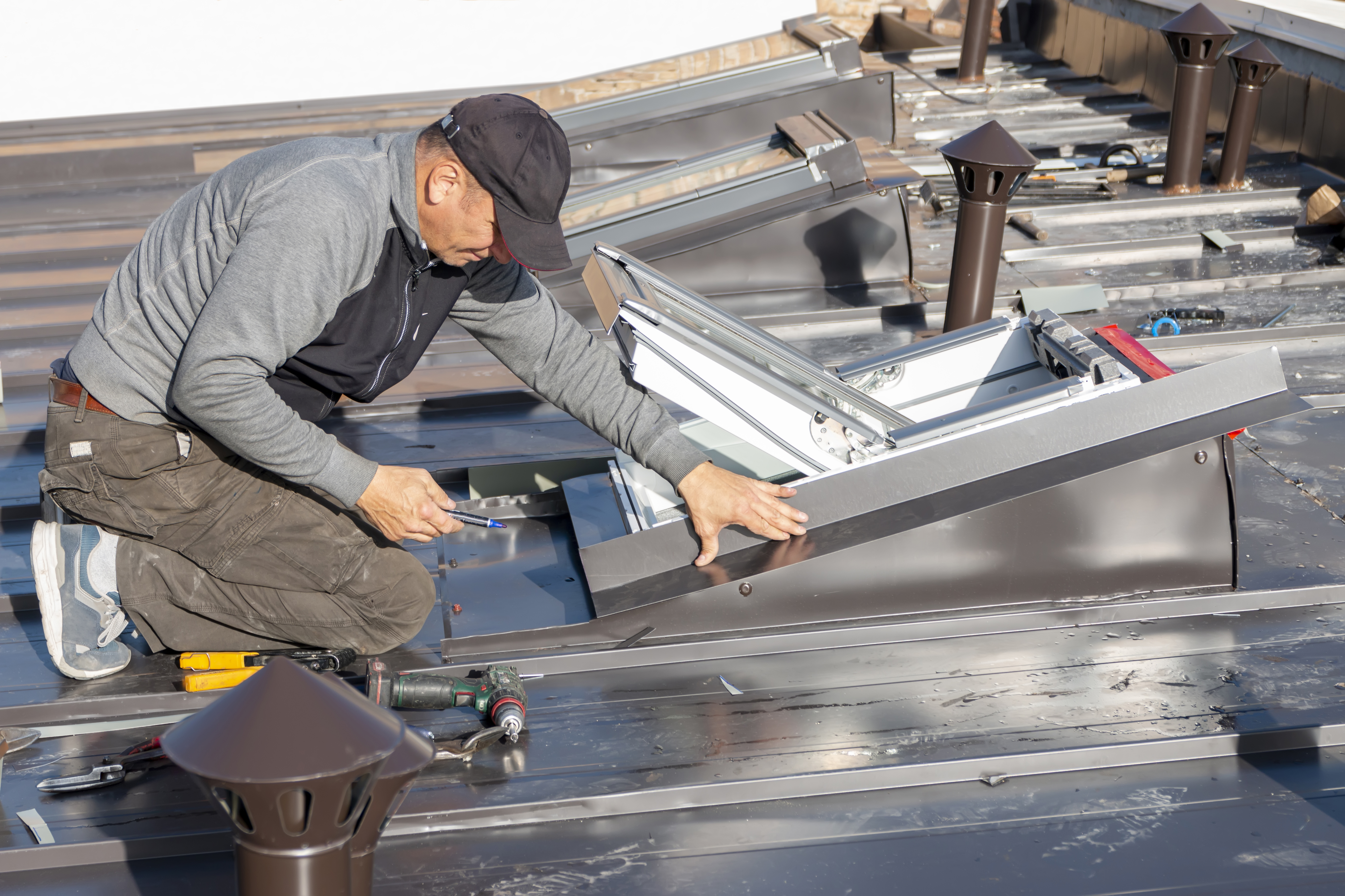 Contractor installing skylight window on a metal roof